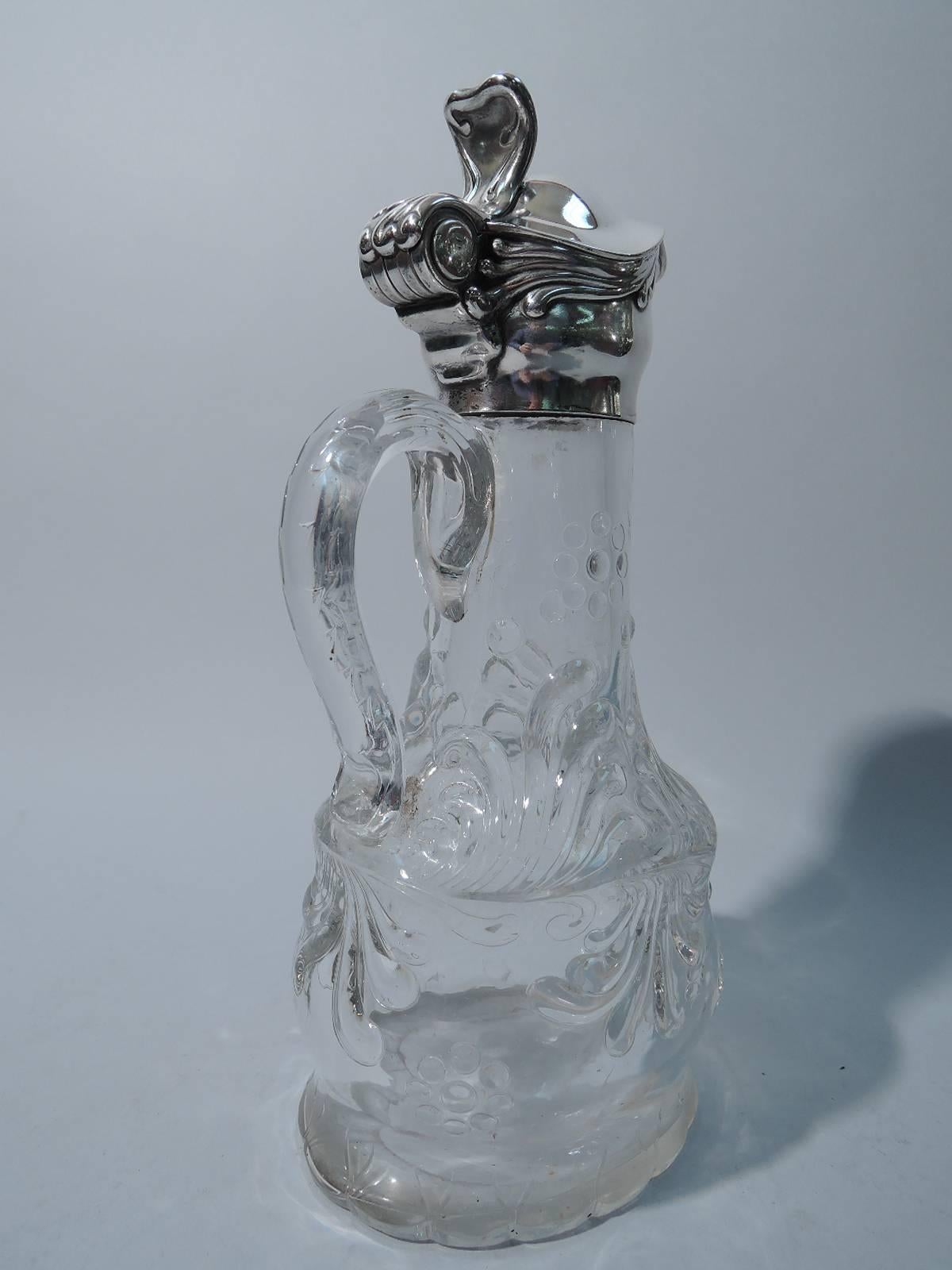 Art Nouveau sterling silver and crystal decanter. Made by Tiffany & Co. Bombe and ovoid with cylindrical neck and scroll handle with foliate cap. Low relief foliage and dot clusters (possibly abstract grape bunches). Silver collar and hinged cover