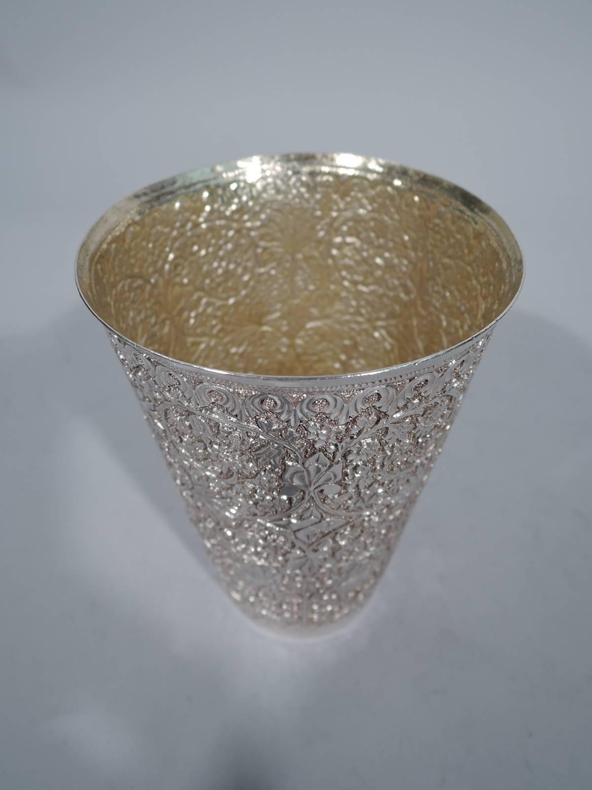 Antique Indian silver tumbler. Straight and tapering sides with dense repousse flowers and tendrils on stippled ground. Perfect for nimbu. Lightly gilt interior.

Dimensions: H 5 1/8 x D 3 ½ in. Weight: 7.2 troy ounces.