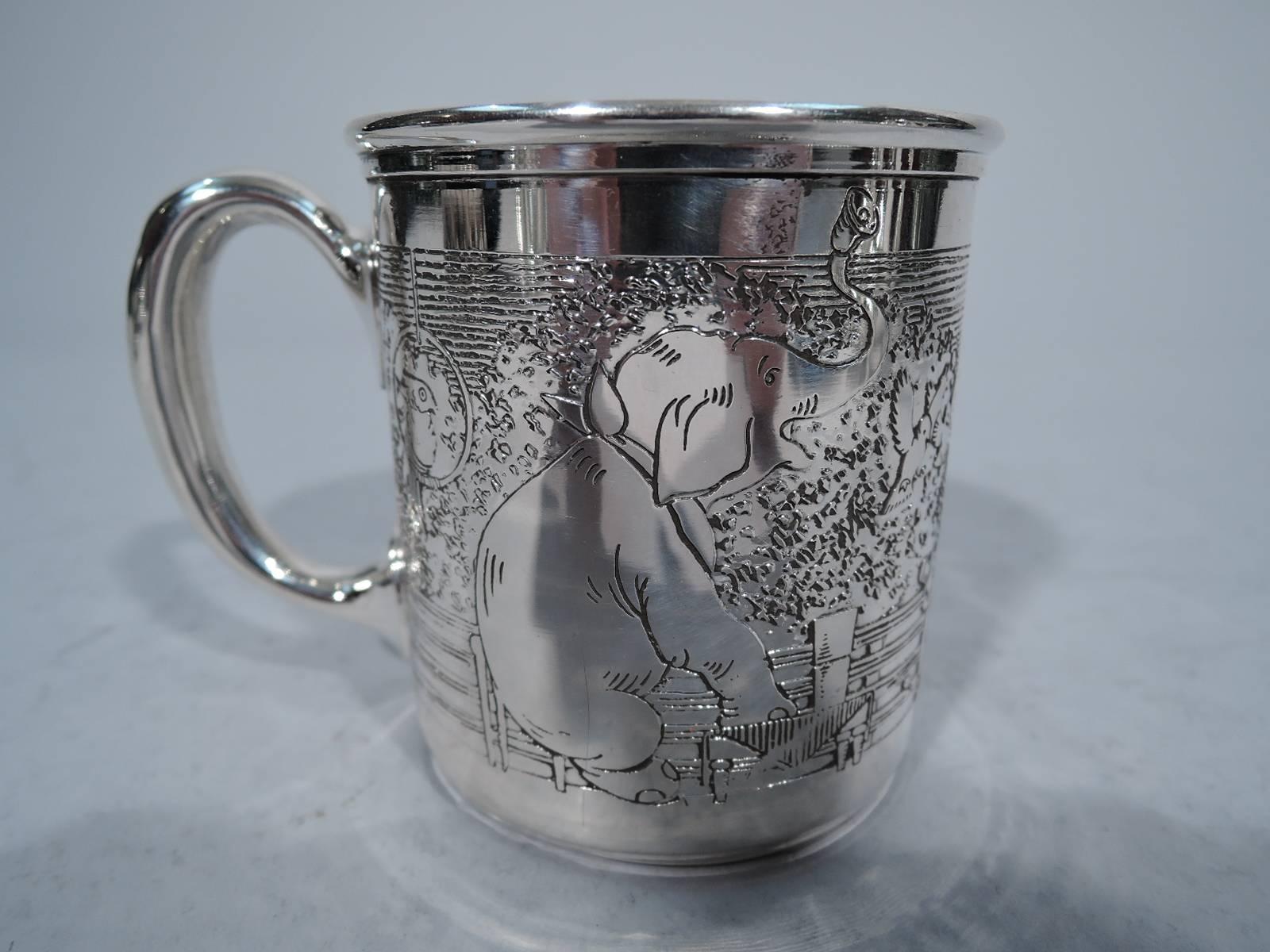 Sterling silver baby cup. Made by HR Morss & Co. in North Attleboro, circa 1930. Straight sides, molded rim and C-scroll handle. Acid-etched circus frieze with giraffe, elephant, dancing dog, and clown surrounding a vacant cartouche where can be