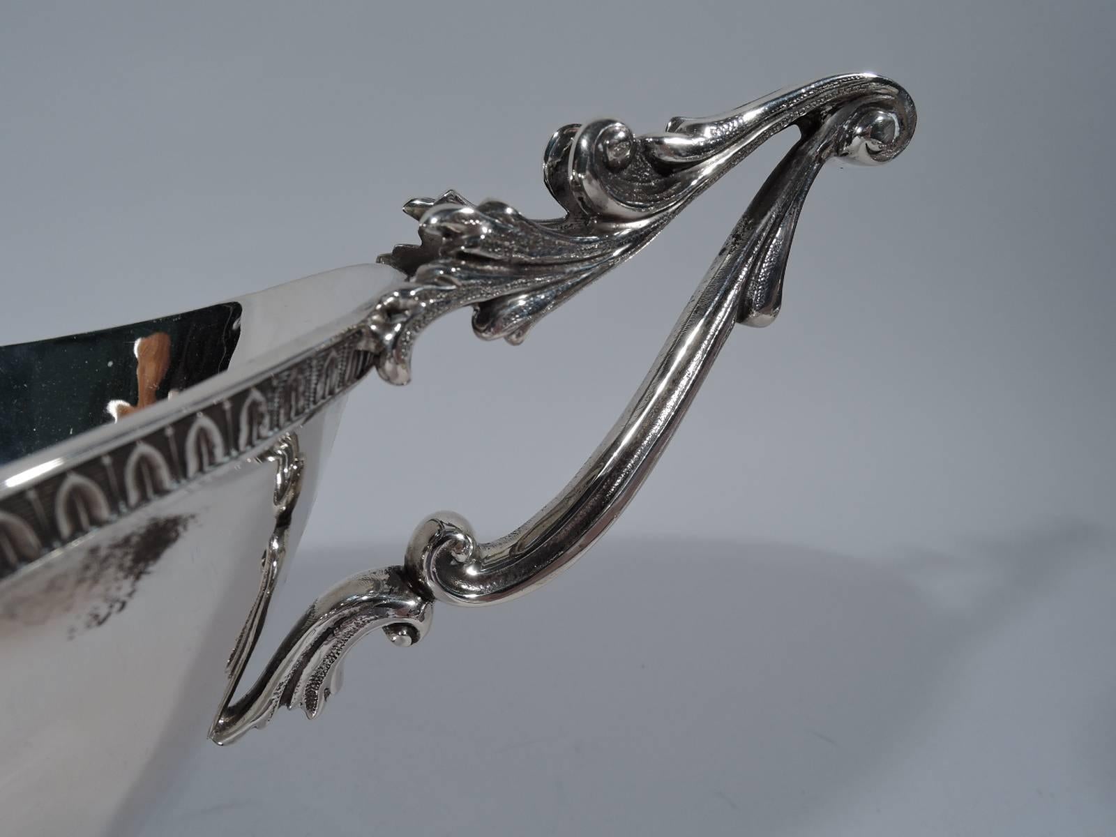 Italian neoclassical 800 silver bowl. Boat-form bowl on raised oval foot. Scrolled bracket end handles with split-leaf mounts. Leaf-and-dart borders. Visible hand hammering. Hallmarked (1944-68). Weight: 23.5 troy ounces.