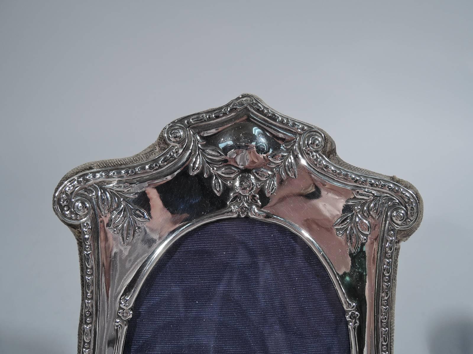 Edwardian Art Nouveau sterling silver picture frame. Made in Birmingham in 1907. Oval window with floral and foliate ornament. Shaped top and bracket feet with volute scrolls. Frame mounted to velvet back with hinged support. With glass and silk
