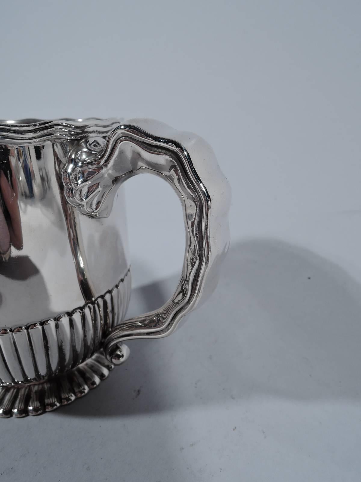 Sterling silver baby cup. Made by Gorham in Providence. Straight sides curved at bottom on flat foot. Top part vacant lots of room for engraving. Bottom and foot gadrooned. Reeded wavy rim. Notched scroll handle. Hallmark includes no. 3860 and