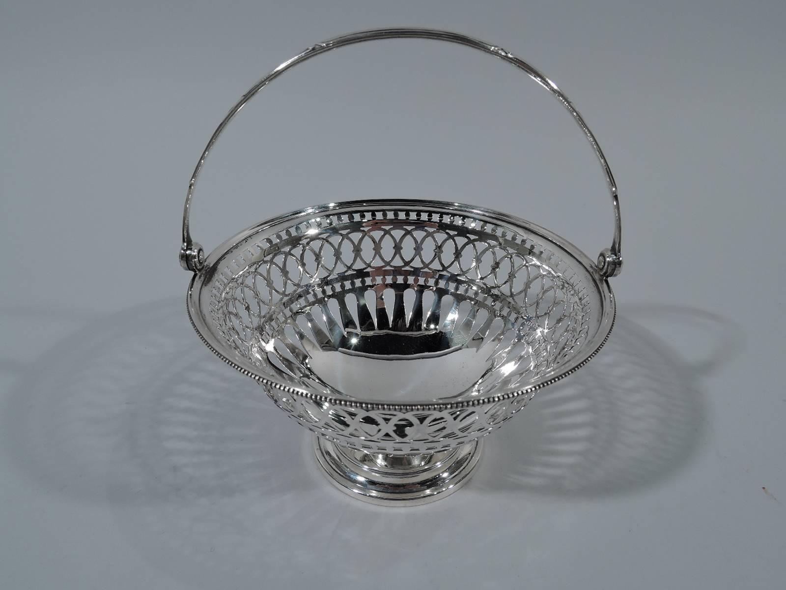 Pretty Edwardian sterling silver basket. Made by Gorham in Providence in 1897. Curved sides with geometric piercing and solid well. Beaded rim. Swing handle and stepped foot. Hallmark includes date symbol and no. 4925. 

H (with handle) 6 5/8 x D