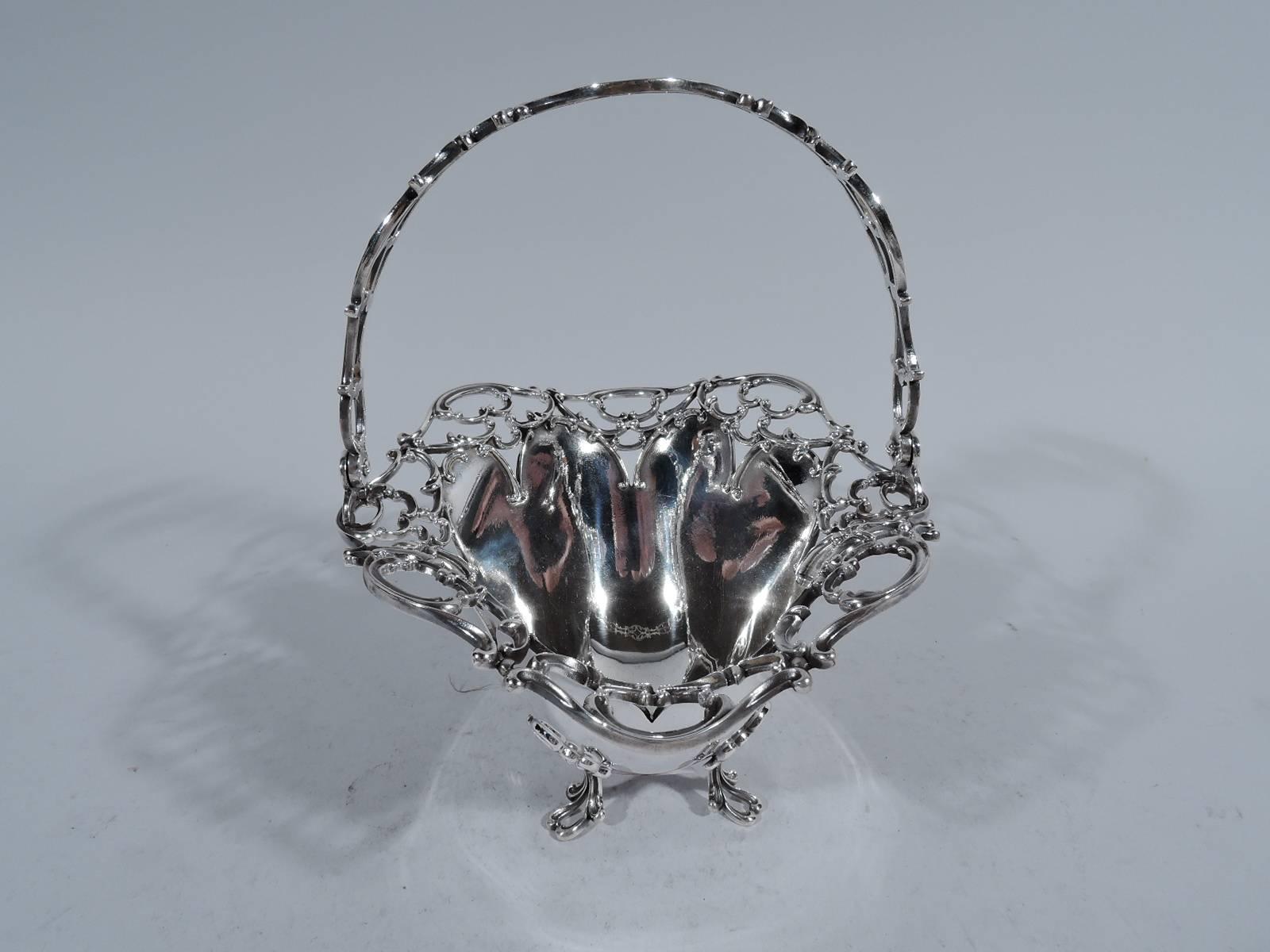 Edwardian sterling silver basket. Made by Towle in Newburyport, Mass., circa 1910. Deep and solid well with open scrollwork applied to scalloped rim. Open scrollwork swing handle and four supports same. Hallmark includes no. 8273.

Dimensions: H