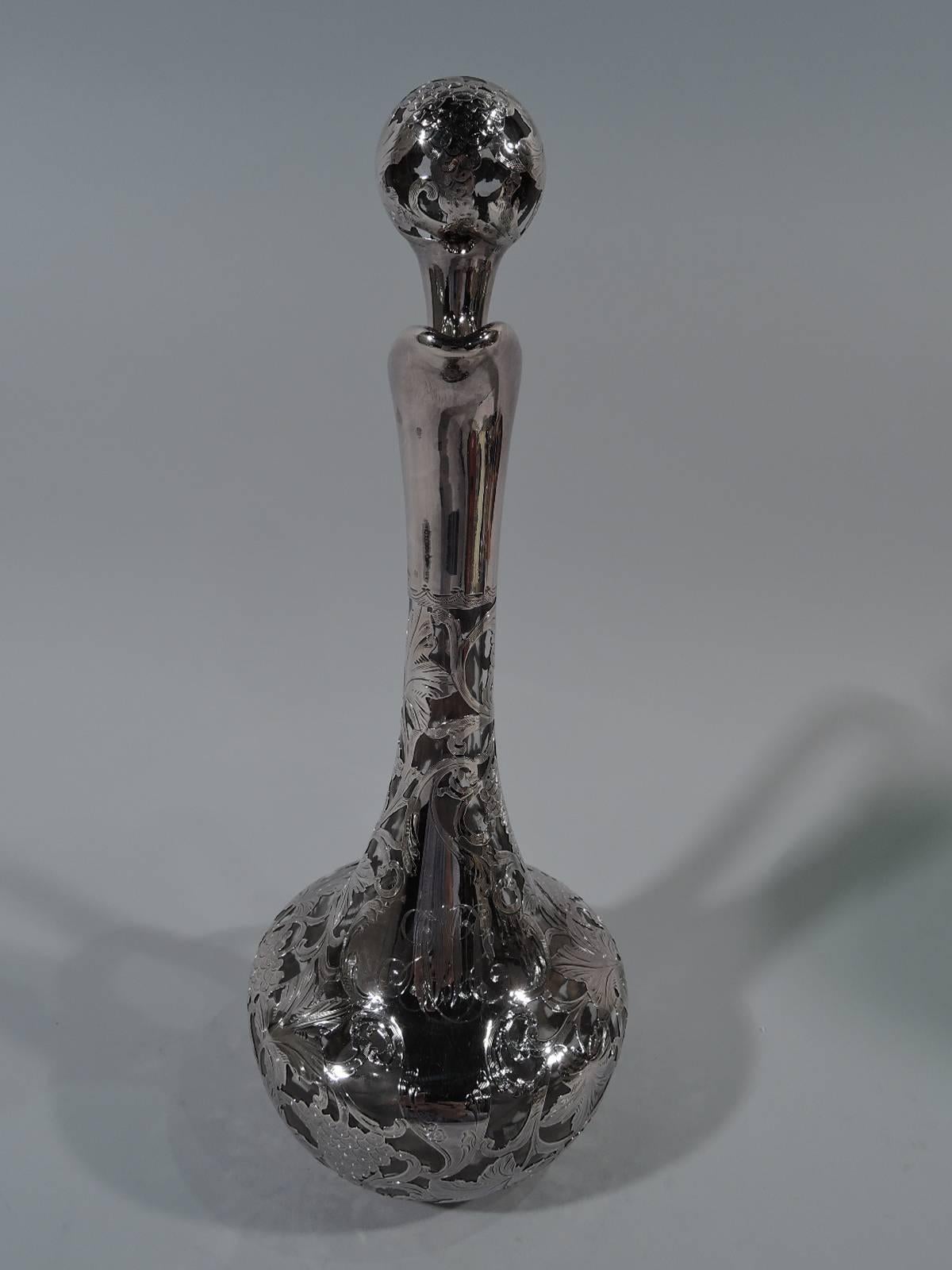 Art Nouveau clear glass decanter with silver overlay. Made by Alvin in Providence, ca 1910. Bellied bowl with upward tapering neck, helmet mouth, and high-looping handle. Overlaid ornament in form of fruiting grapevine. Asymmetrical cartouche has