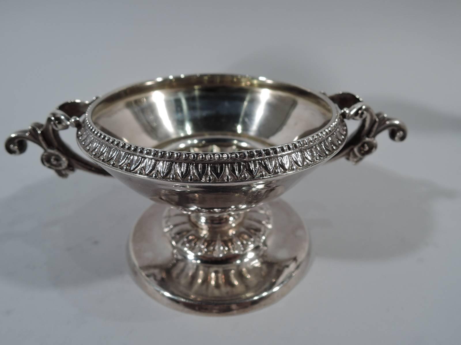 Pair of Classical sterling silver open salts. Made by William Gale in New York in 1862. Each: Conical bowl has raised leaf-and-dart rim and repousse fluting on underside as well as side handles with flowers and split mounts. Circular foot with