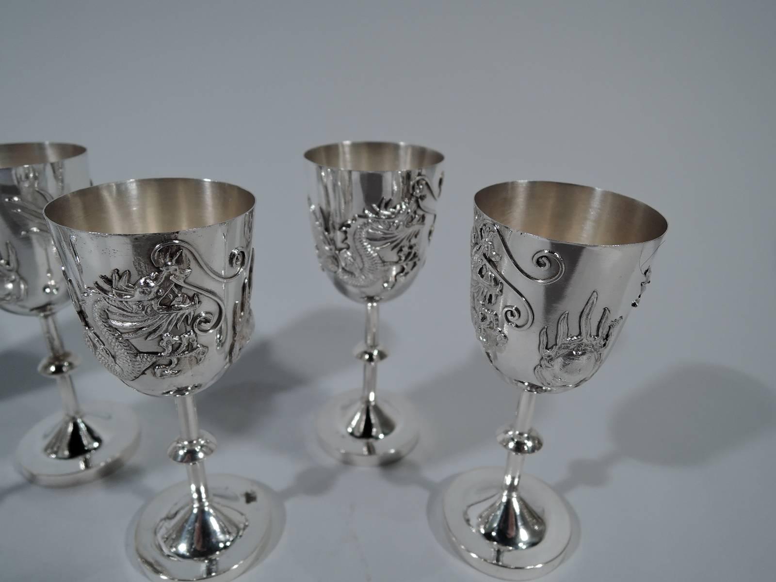 Set of eight Asian export silver cordials, circa 1910. Each: Tapering bowl on knopped stem on raised foot mounted to round base. Scary, scaly dragon applied to bowl as well as an unidentified tentacular mass, suggestive of a firewater-induced