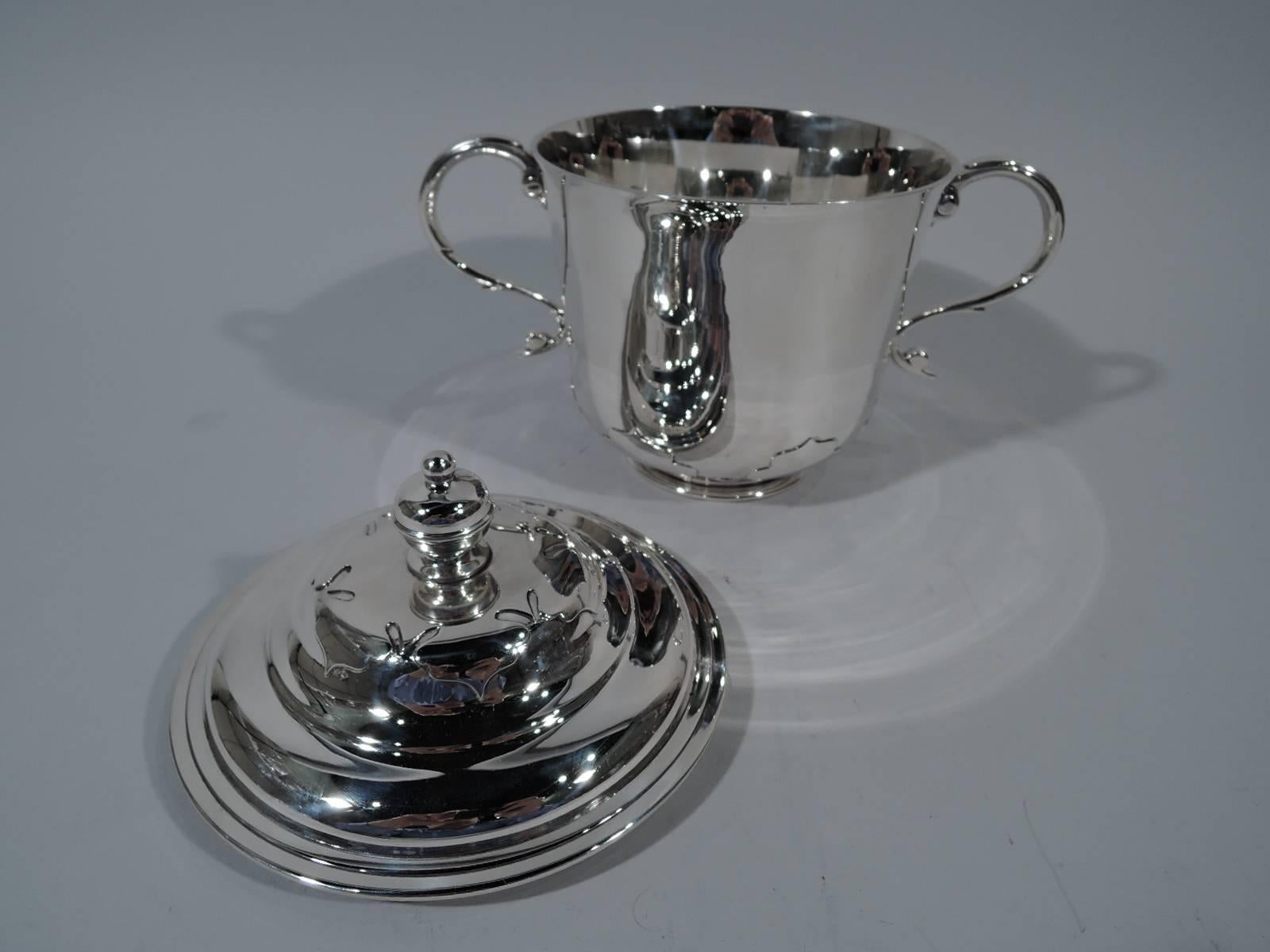 George V sterling silver trophy cup. Made by Daniel & John Wellby in London in 1913. Bowl has flared rim, capped s-scroll side handles, and inset stepped foot. Cover double-domed with vase finial. Cut-out shapes applied to cover and bowl base for a