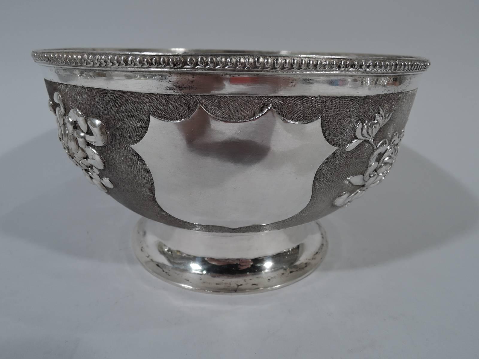 Beautiful Chinese export silver bowl, circa 1900. Curved sides and raised spread foot. Raised and naturalistic chrysanthemums on stippled ground and beaded rim. Foot plain. One circular frame and one armorial frame (both vacant). Marked with Chinese