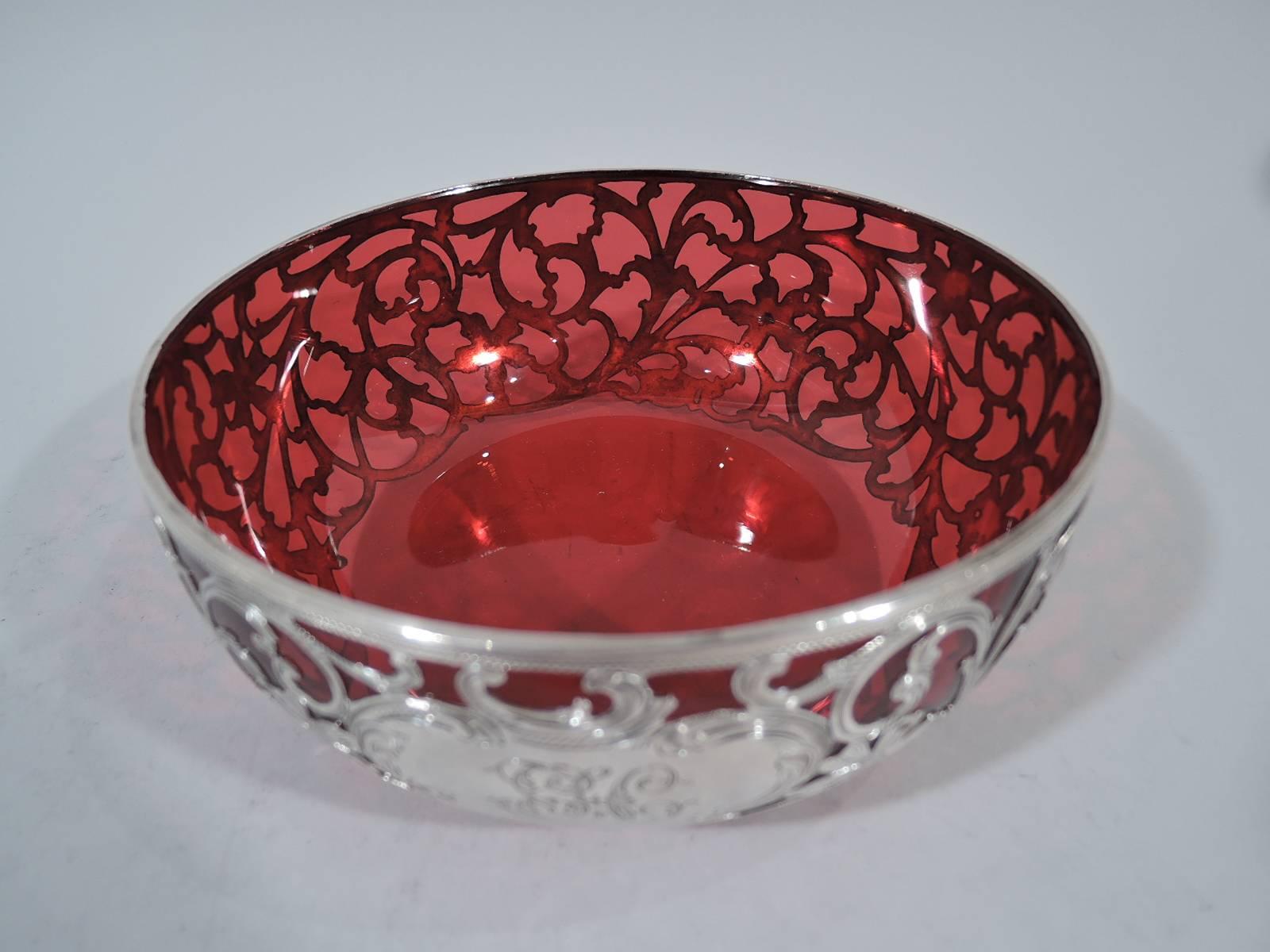 Art Nouveau red glass bowl with silver overlay. Made by Alvin in Providence, circa 1910. Shallow with curved sides. Rinceaux overlay with naturalistic flowers and scrolls. Ground down pontil mark. Hallmark includes no. R399.