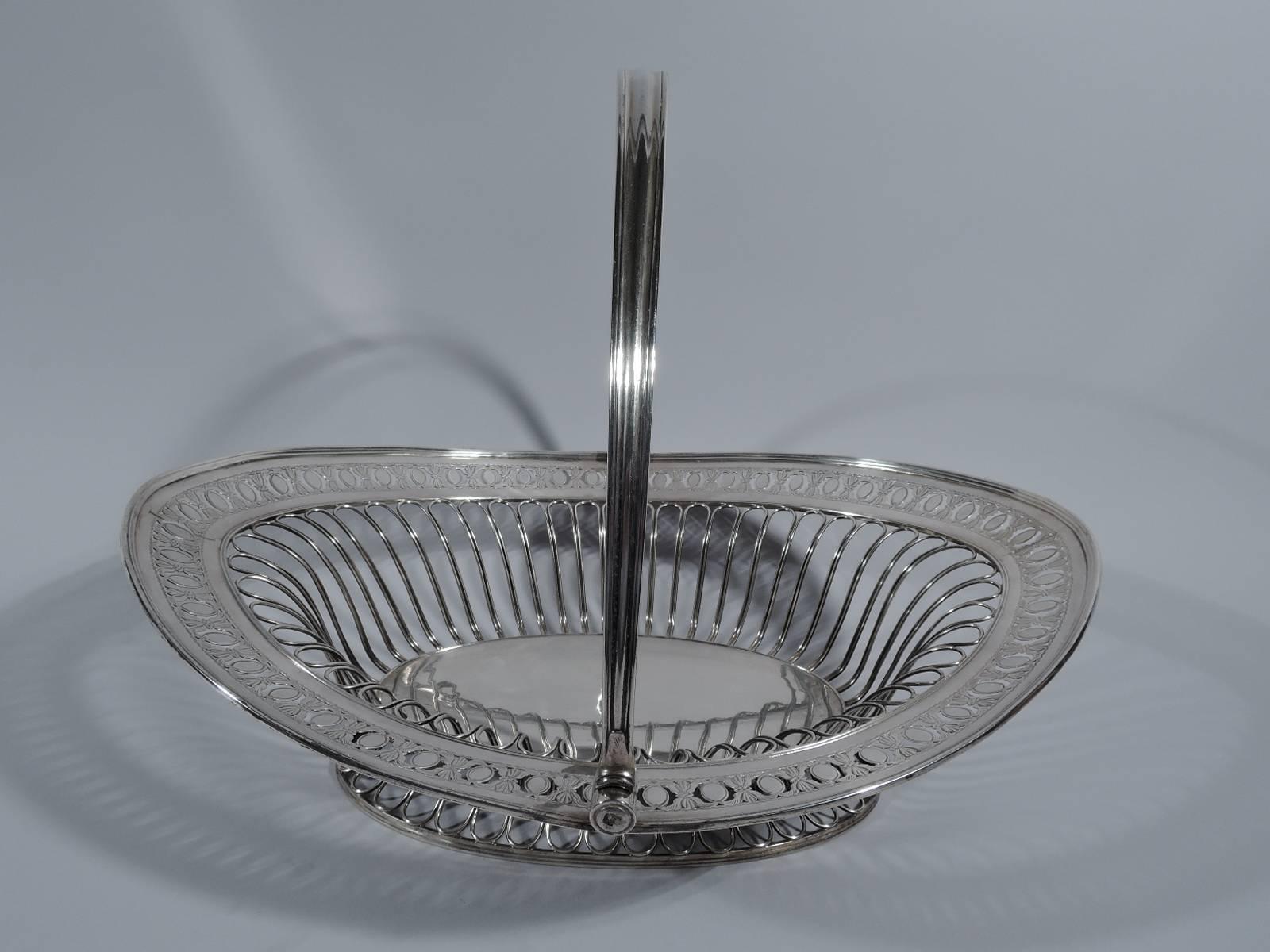 George III sterling silver basket. Made by Nathaniel Smith & Co. in Sheffield in 1791. Solid oval well, open wired gadrooning on sides, spread foot same, and pierced ornamental border. Tapering and molded c-scroll swing handle. Hallmarked.