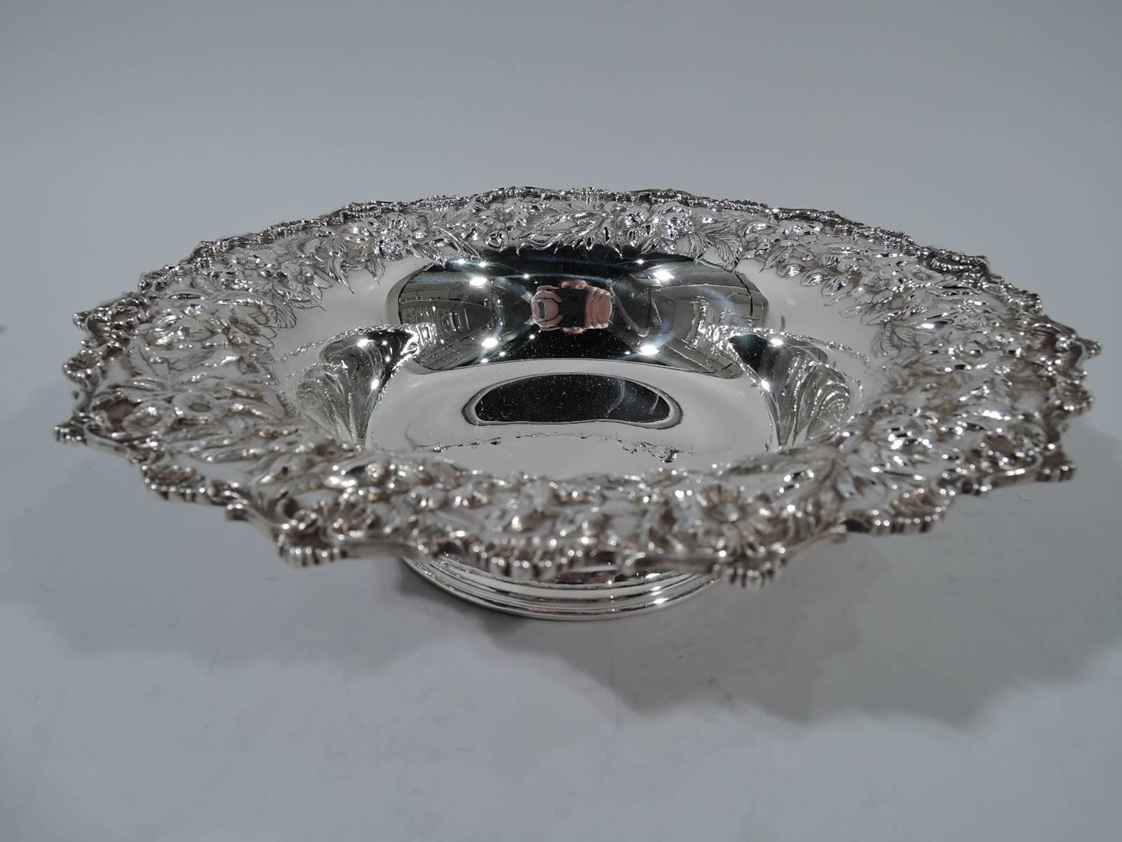 Sterling silver bowl. Made by S. Kirk & Son in Baltimore. Plain well and wide rim with repousse flowers and scrolled rim with applied c-scrolls, leaves and scallop shells. Spread foot. An attractive modernization of the traditional Baltimore look.