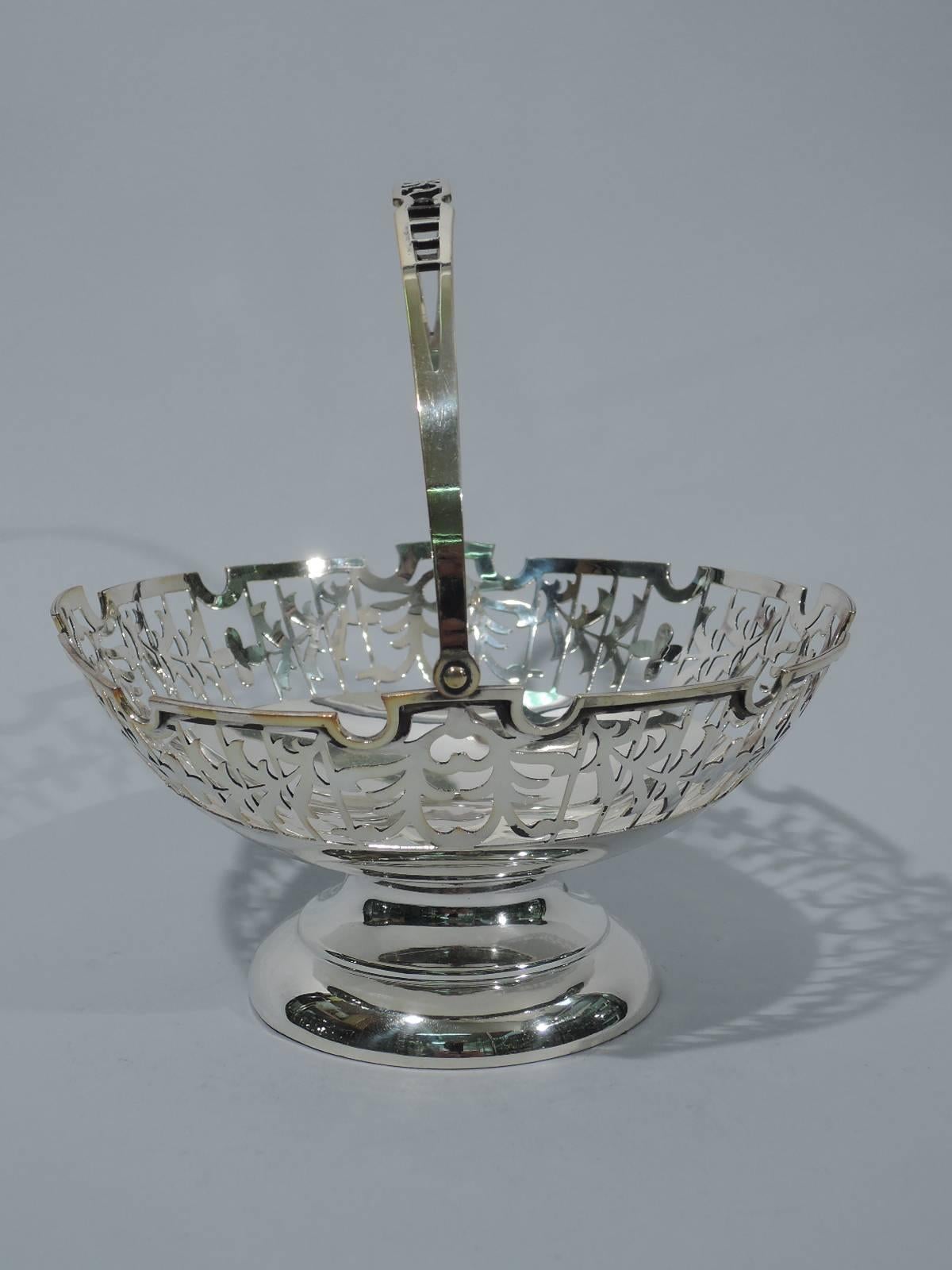 Chinese Export silver footed basket, circa 1910. Solid well and open sides with garland on trellis. C-scroll swing handle with same. Molded curvilinear rim. Short concave stem and stepped foot. Hallmarked with Chinese characters.

Dimensions: H