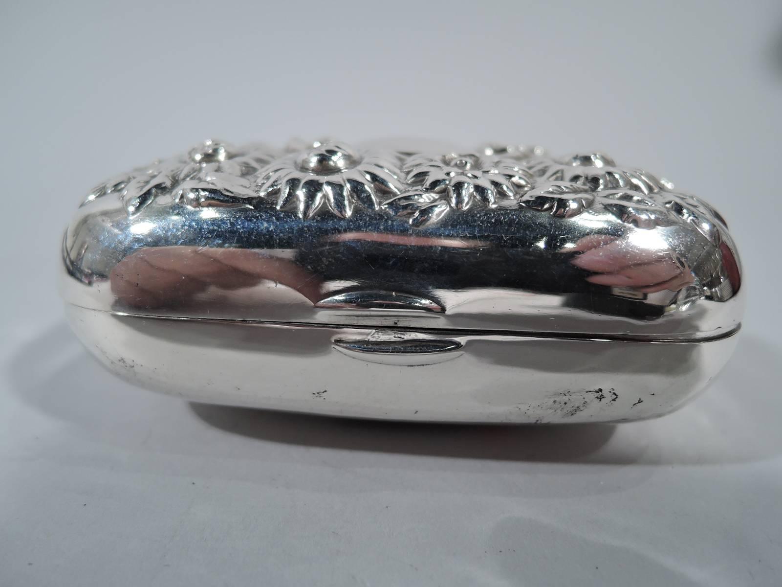 American sterling silver soap box, circa 1900. Rectangular with curved corners and hinged cover. Cover has central scrolled frame (vacant) surrounded by dense repousse daisies. Hallmarked “sterling”. Very good condition with nice definition. Weight: