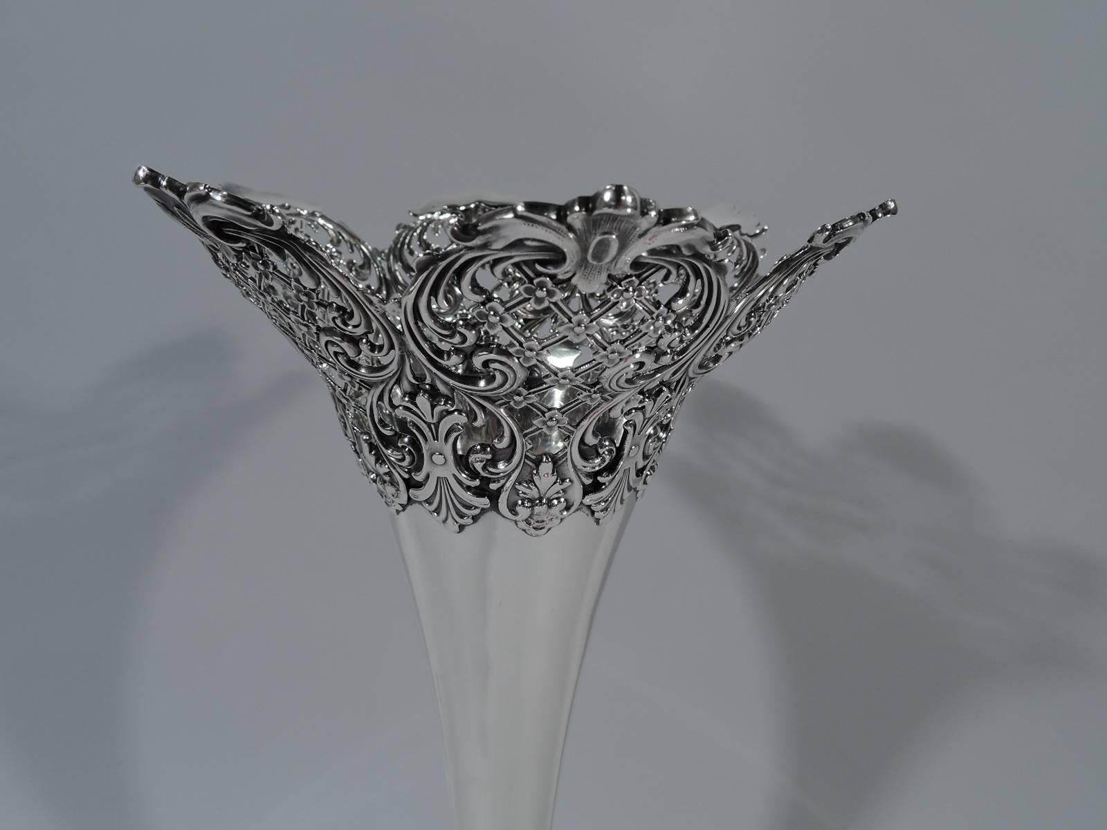 Edwardian sterling silver vase. Made by Redlich in New York, circa 1910. Trumpet vase on knop on dome foot. Pierced and applied rim and foot rim: Leaf-mounted scrolled frames inset with floral diaper ornament and surmounted by leaves. A successful