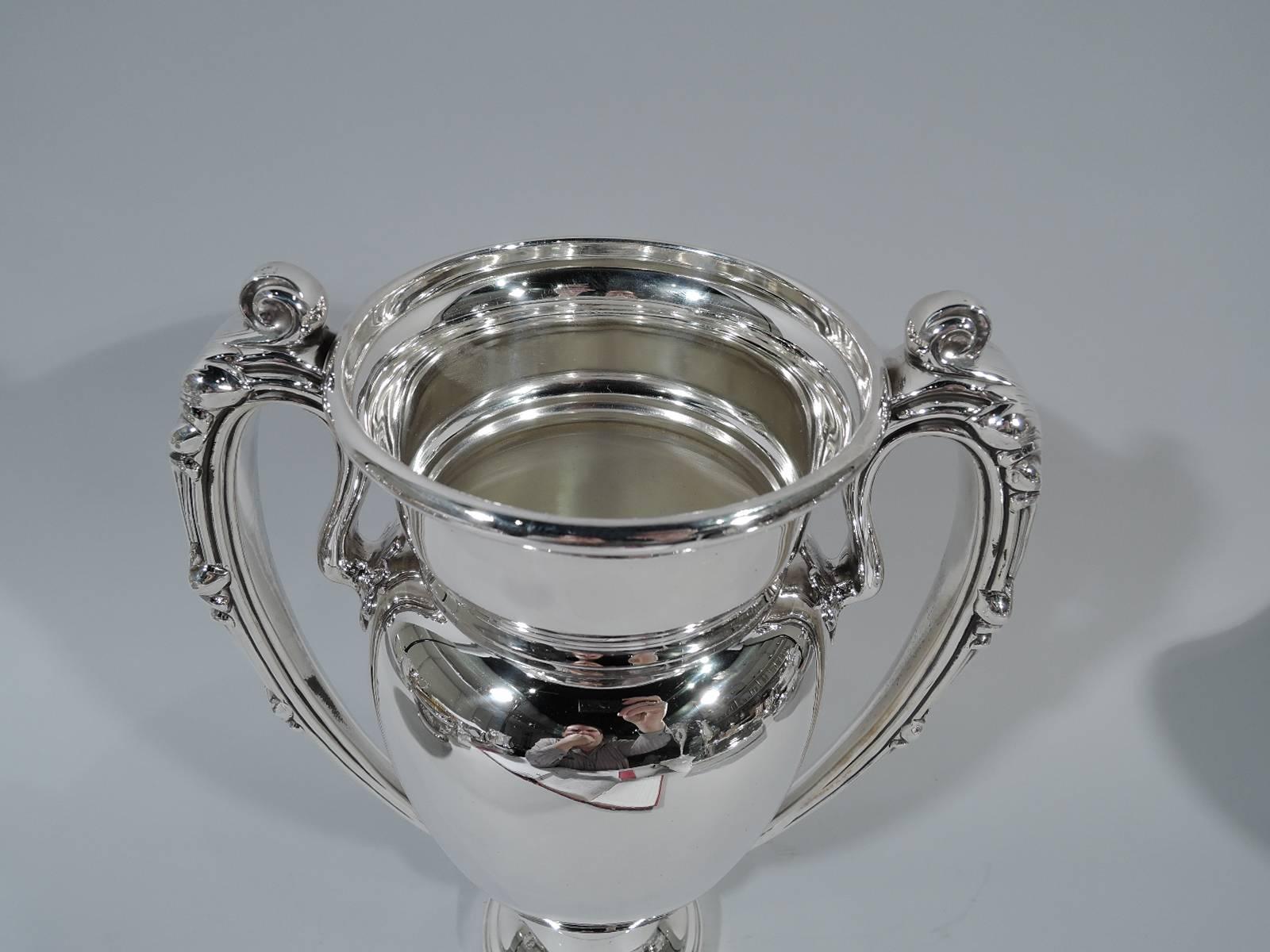 Sterling silver trophy cup. Made by Meriden Britannia (part of International) in Meriden, Conn., circa 1910. Amphora with reeded and leaf-capped high-looping scroll handle and stepped and domed foot. Sleek classicism. Lots of room for engraving.