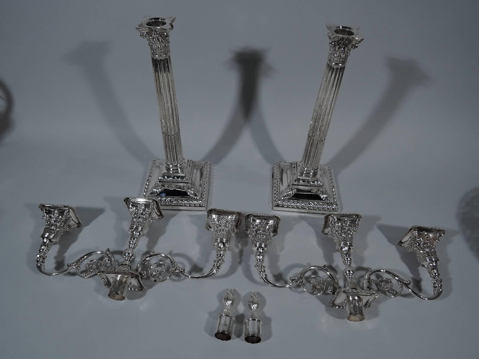 Pair of neoclassical sterling silver candelabra. Made by Henry Wilkinson & Co. in England, 1893-94. Each: Tall column with stop fluting on stepped square base. Central socket with flame finial between two capped rinceaux arms each terminating in