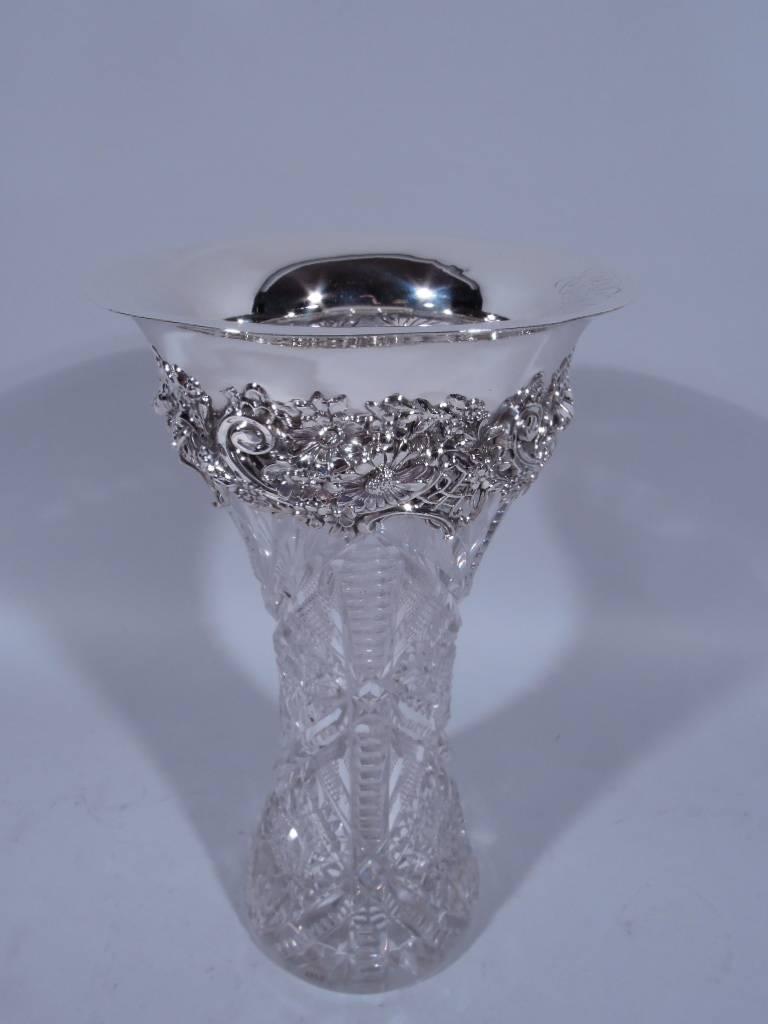 Brilliant-cut glass vase with sterling silver collar. Made by Redlich in New York, circa 1900. Waisted cylinder with dense fans, stars and diaper and notched ornament. Collar has dense applied flowers and scrolls as well as plain and flared rim.