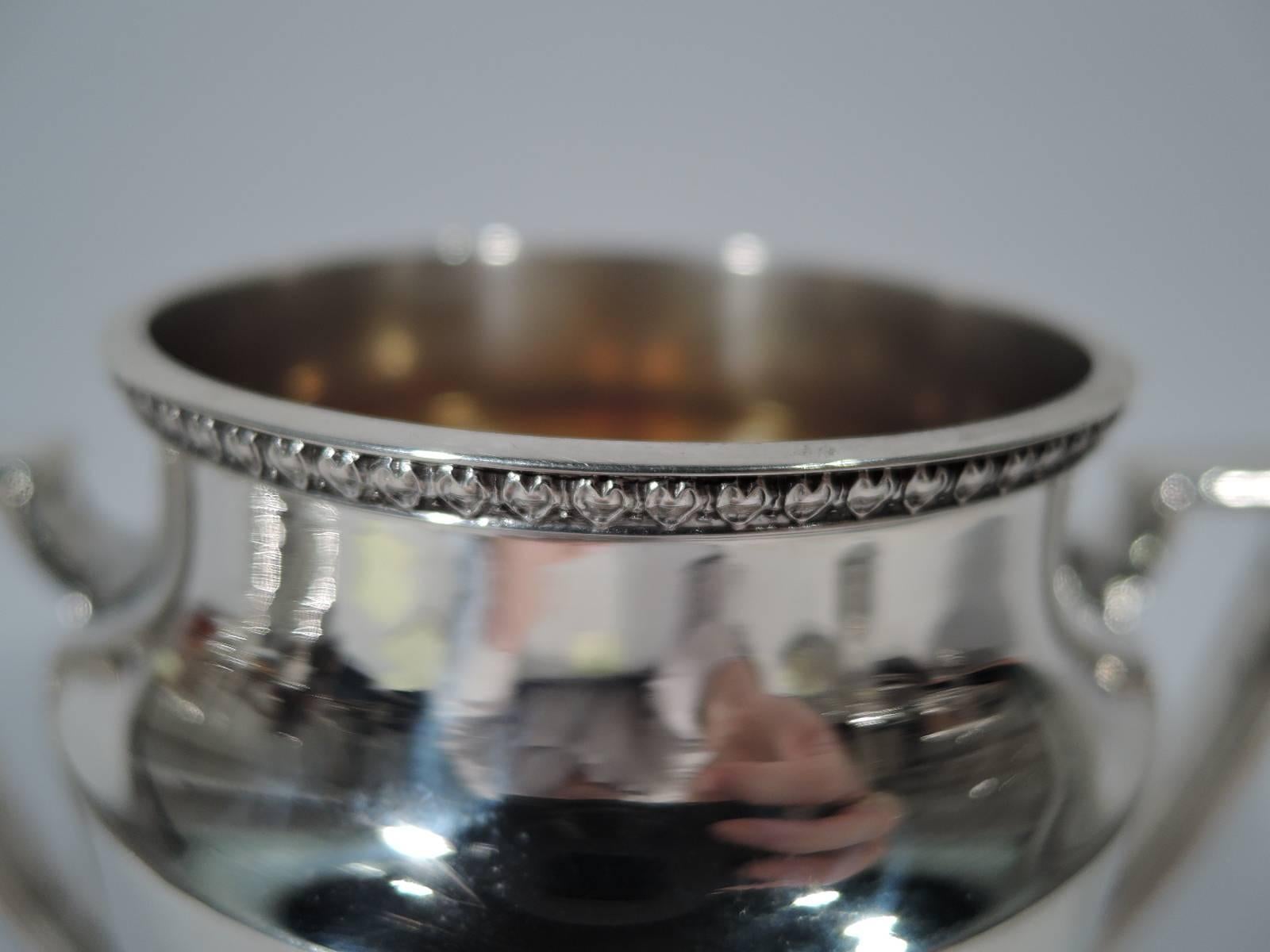Sterling silver trophy cup. Made by R. Wallace & Sons Mfg Co. in Wallingford, circa 1940. Tapering bowl with raised border, inset mouth, and leaf-and-dart rim. Scrolled bracket handles and stepped foot. Gilt interior. Hallmark includes no. 2739.