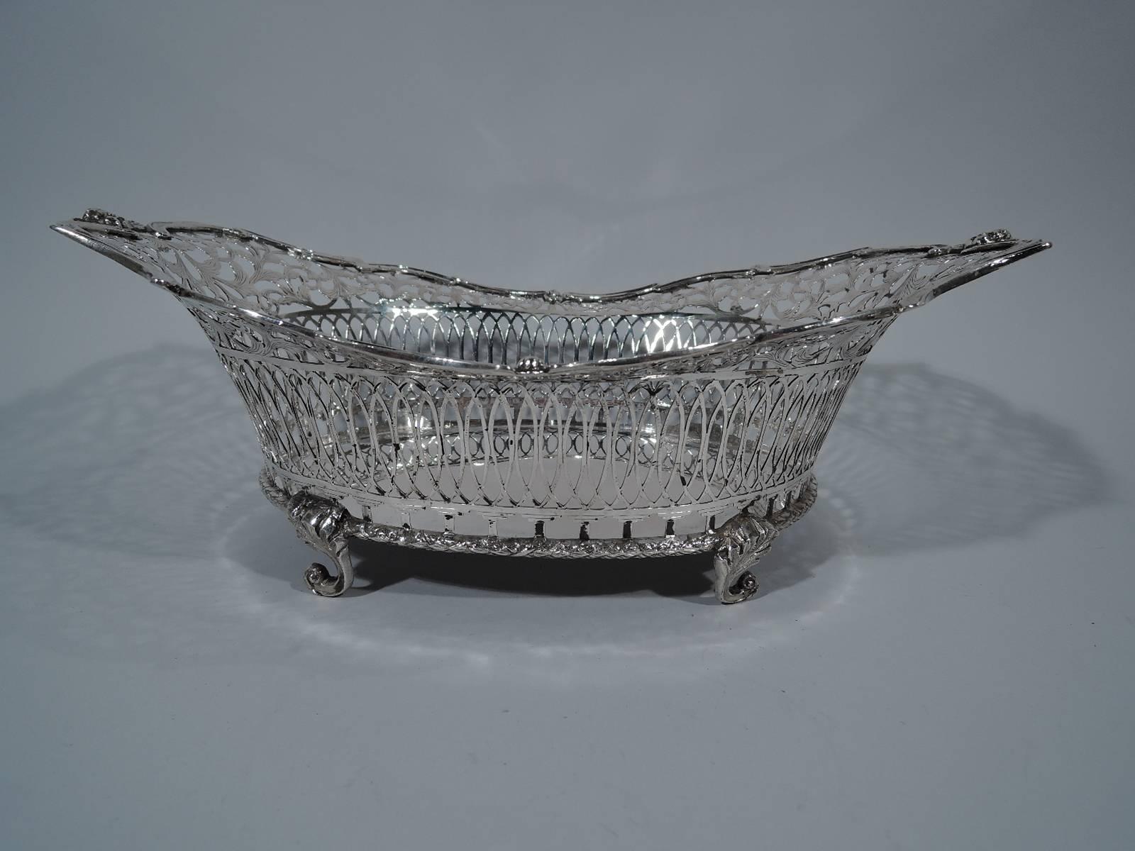Dutch 833 silver basket, circa 1910. Solid oval well and open sides with colonnade supporting interlaced ovals, in turn, supporting foliate scrollwork heightened with engraving. Rim has applied overlapping C-scrolls and winged cupid heads at ends.
