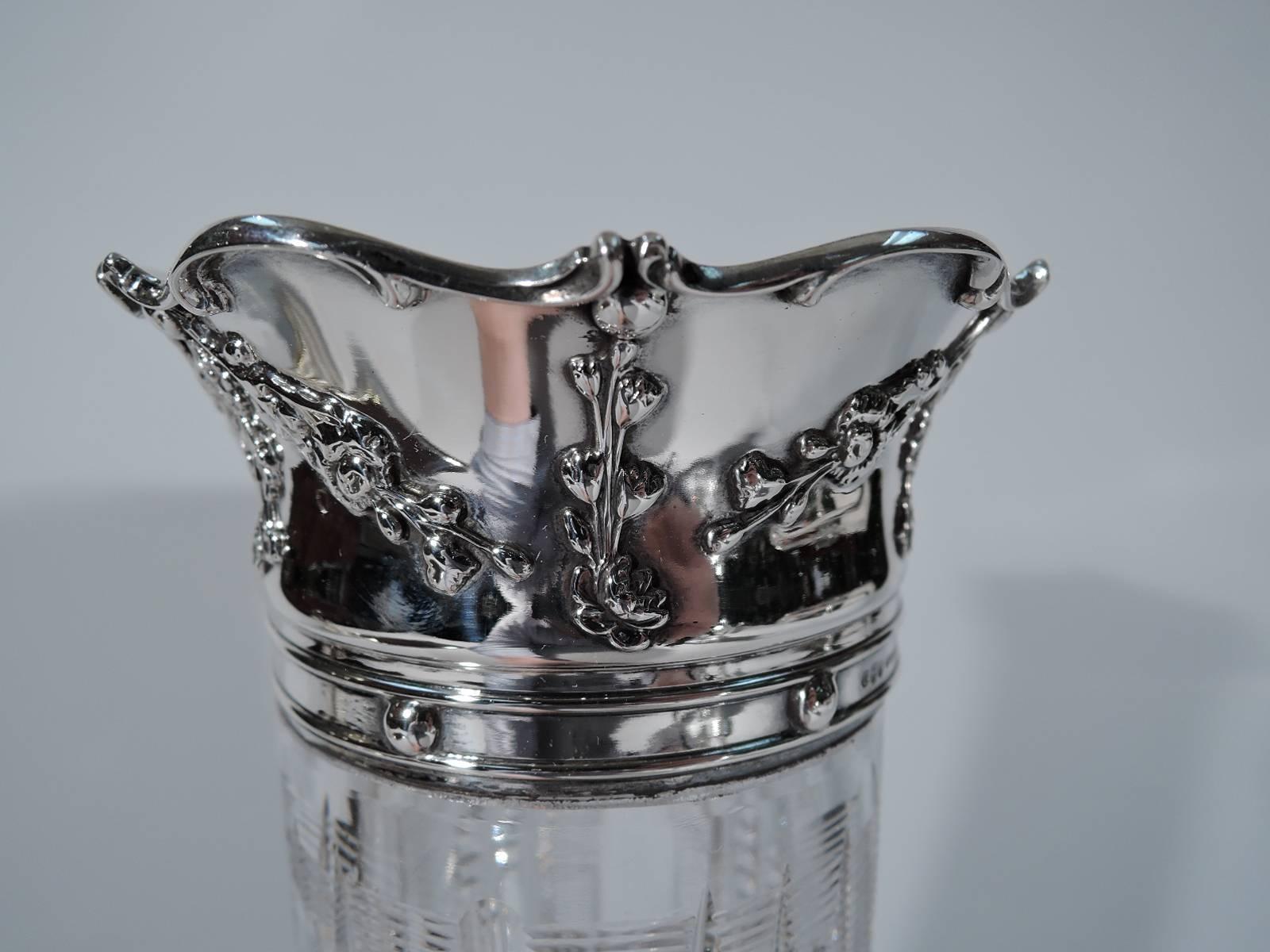 Brilliant cut-glass vase with sterling silver collar. Made by Gorham in Providence, circa 1900. Cylindrical with spread base. Vertical ornament with alternating flutes, ribbing, and notching as well as fans and lozenges with inset circles at base.