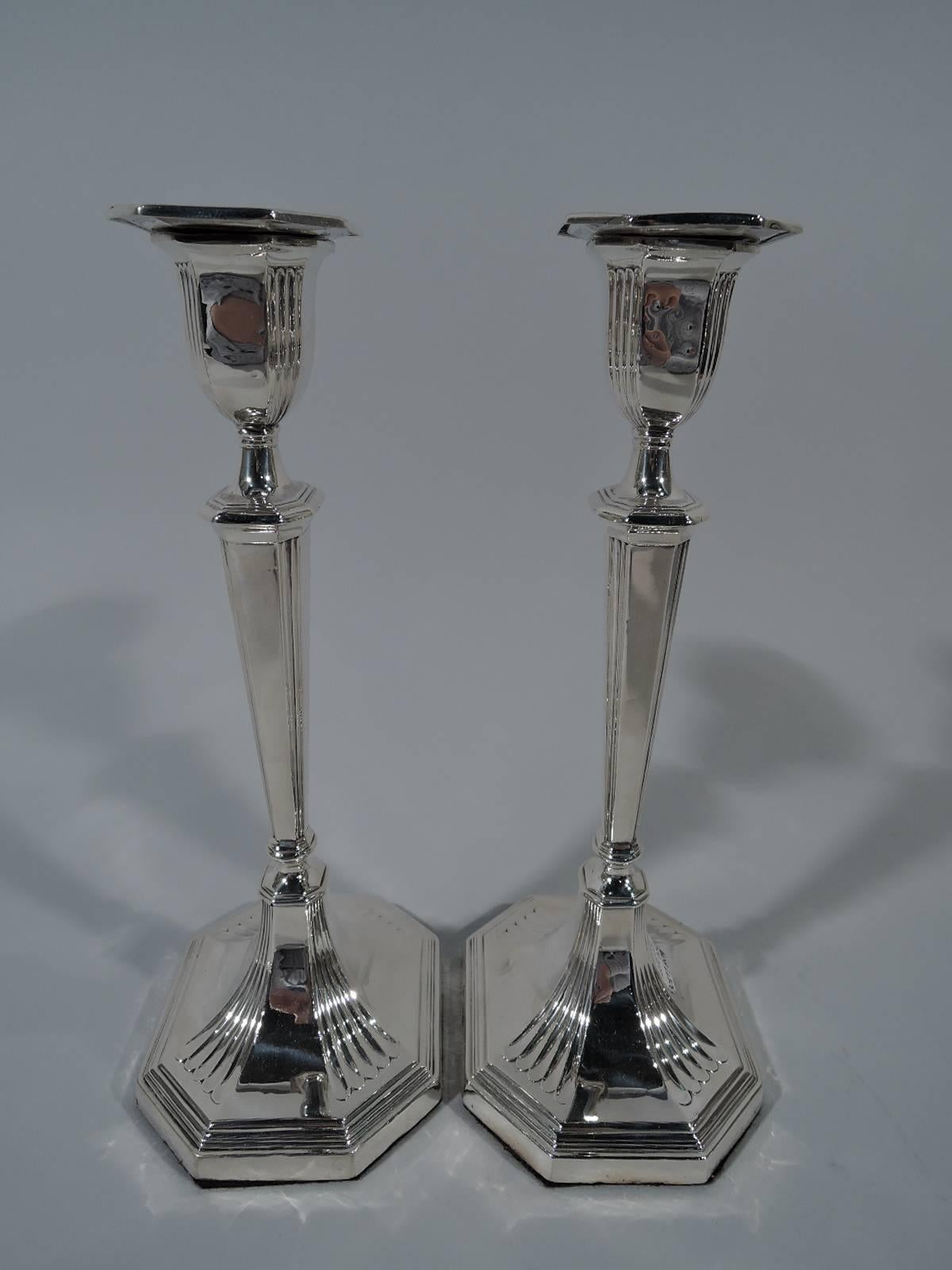 Pair of Edwardian sterling silver candlesticks. Made by William Hutton & Sons in London in 1901. Each: Classic tapering pillar with chamfered rectangular detachable bobeche. Foot same. Fine reeding. Hallmarked. Weighted.