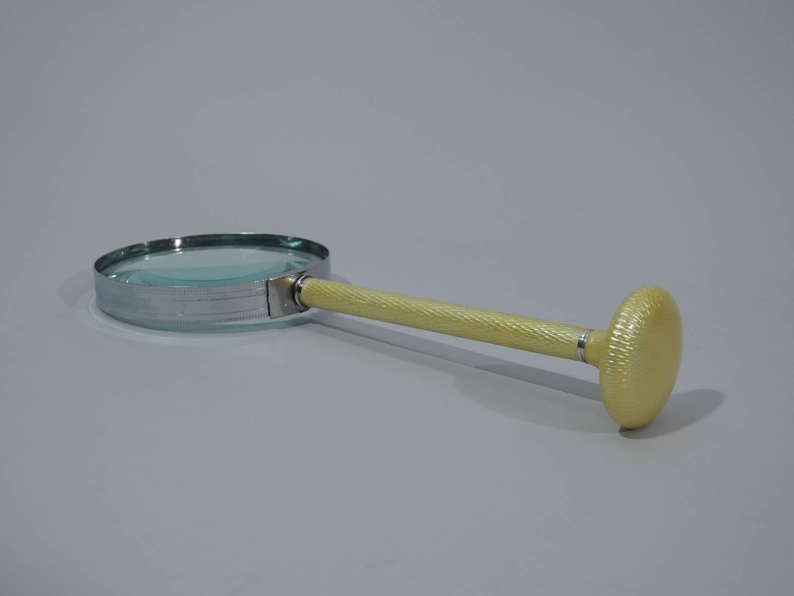 Art Deco magnifying glass, circa 1920. Circular lens mounted to cylindrical handle terminating in perpendicular disc. Handle is in yellow enamel with engine-turned wave pattern. Smart and modern.