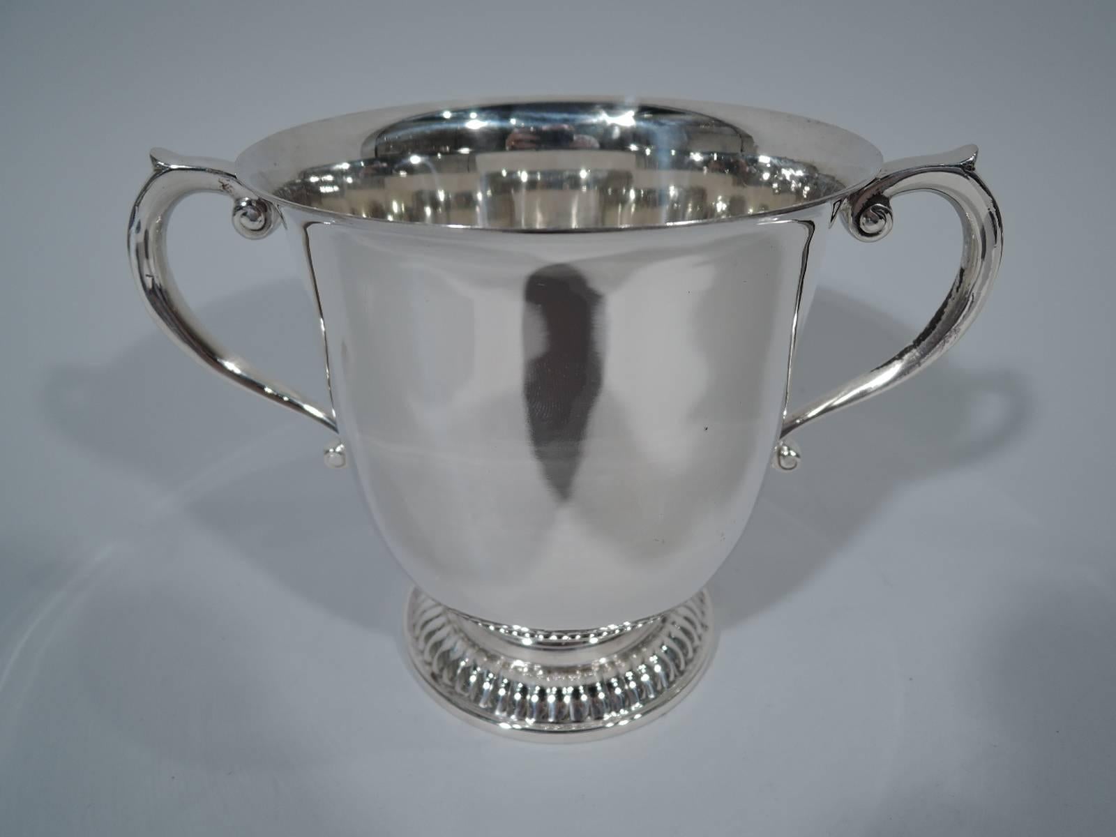Classic sterling silver trophy cup. Made by Tiffany & Co. in New York, circa 1965. Urn with flared rim, capped scroll side handles, and raised and gadrooned foot. Compact with good heft and lots of room for engraving. Hallmarked. Heavy weight: 20