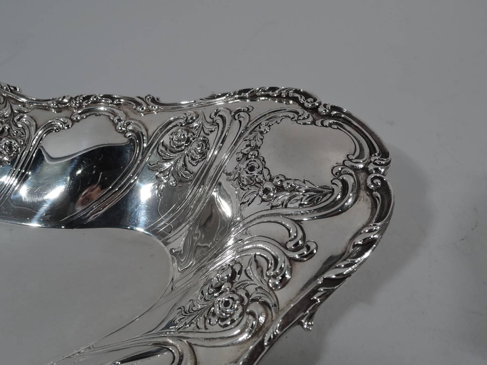 Pretty sterling silver bread tray. Made by Gorham in Providence. Elongated and shaped oval well. Tapering and asymmetrical sides with chased and repousse scrolls, scallop shells, and flowers. Rim has applied scrolls. Hallmark includes no. 593.