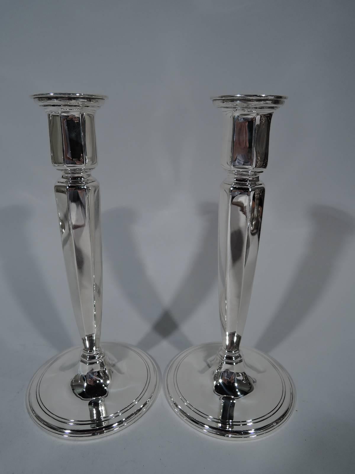 Two pairs of Art Deco sterling silver candlesticks. Made by Tiffany & Co. in New York, circa 1924. Each: tapering and faceted shaft mounted to raised and banded circular foot. Shaft top inset and surmounted by straight and faceted socket. Detachable