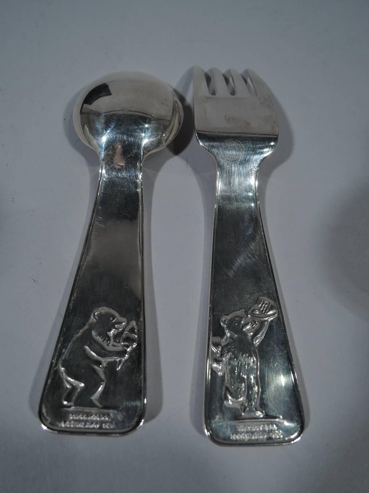 ABC sterling silver baby spoon and fork. Made by Tiffany & Co. in New York. Wide and tapering terminals with acid-etched bears climbing and carrying letters. On terminal back, a bear licks an ice cream cone (spoon) and holds aloft a plate with cake