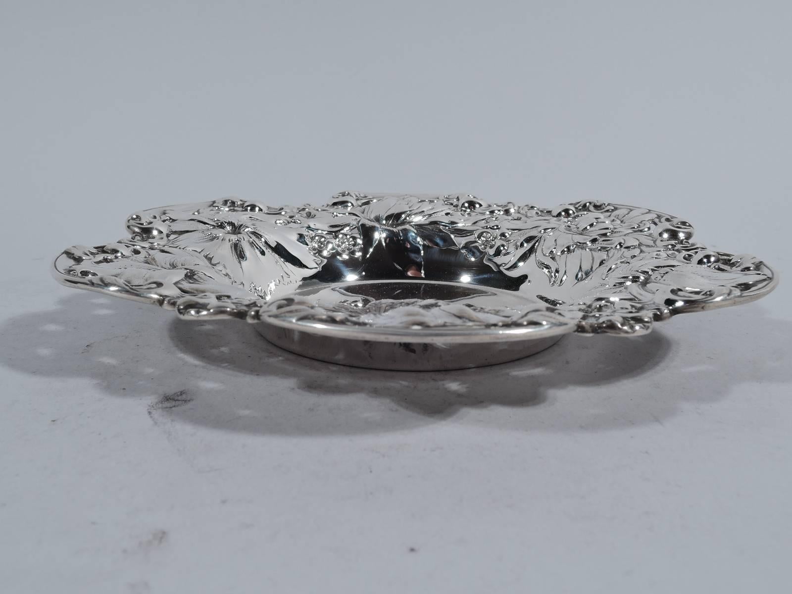 Victorian sterling silver bowl. Made by Gorham in Providence in 1899. Plain circular well and wide and asymmetrical rim with big blooms – dense and overlapping flowers framed by C-scroll rim. Exuberant and tactile. Interlaced script monogram.