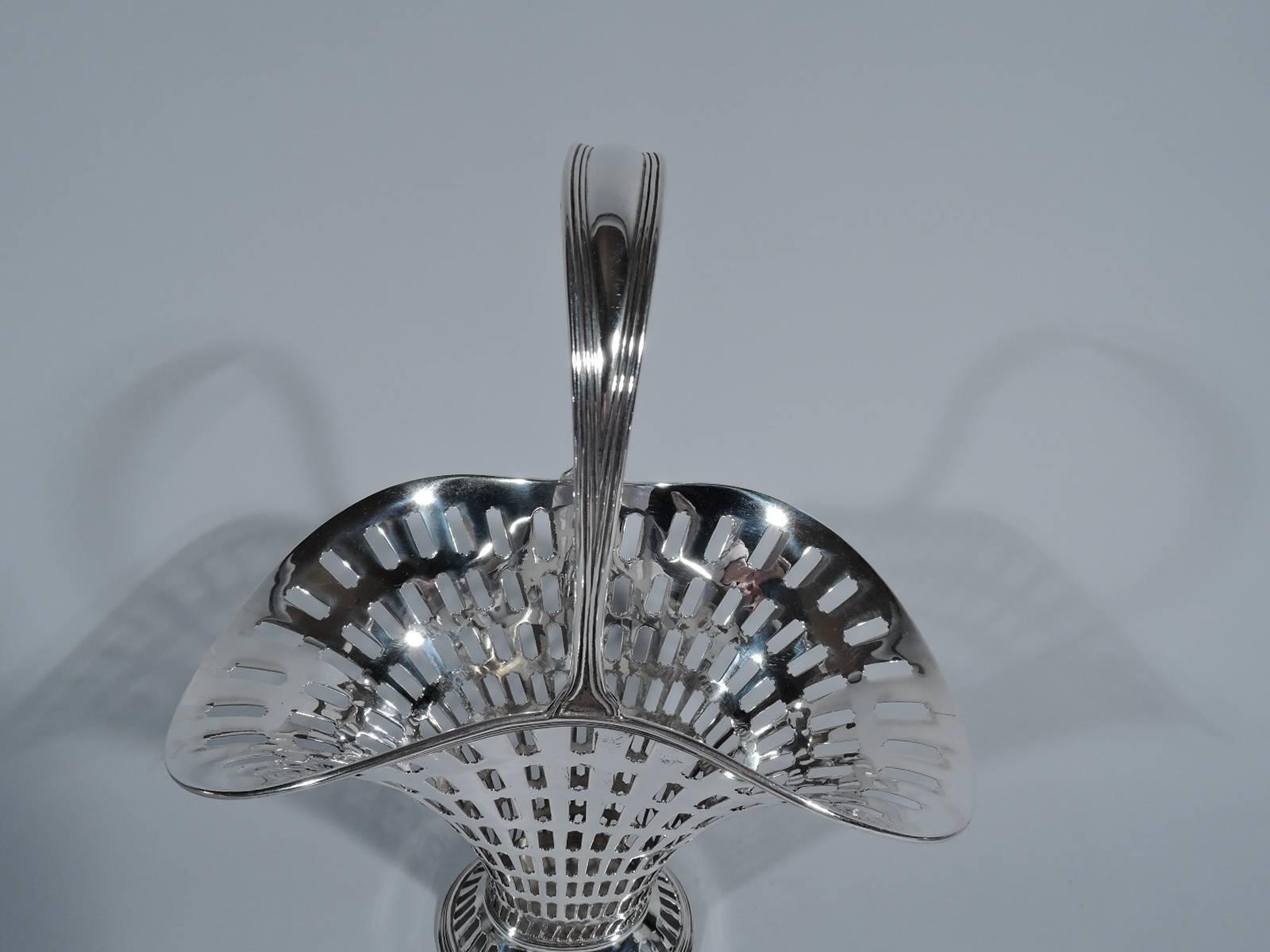 Edwardian sterling silver basket. Made by Tiffany & Co. in New York, circa 1903. Tapering “flattened” ovoid body with flared mouth and spread foot. Reeded and tapering stationary handle. Graduated tubular piercing. Hallmark includes pattern no.