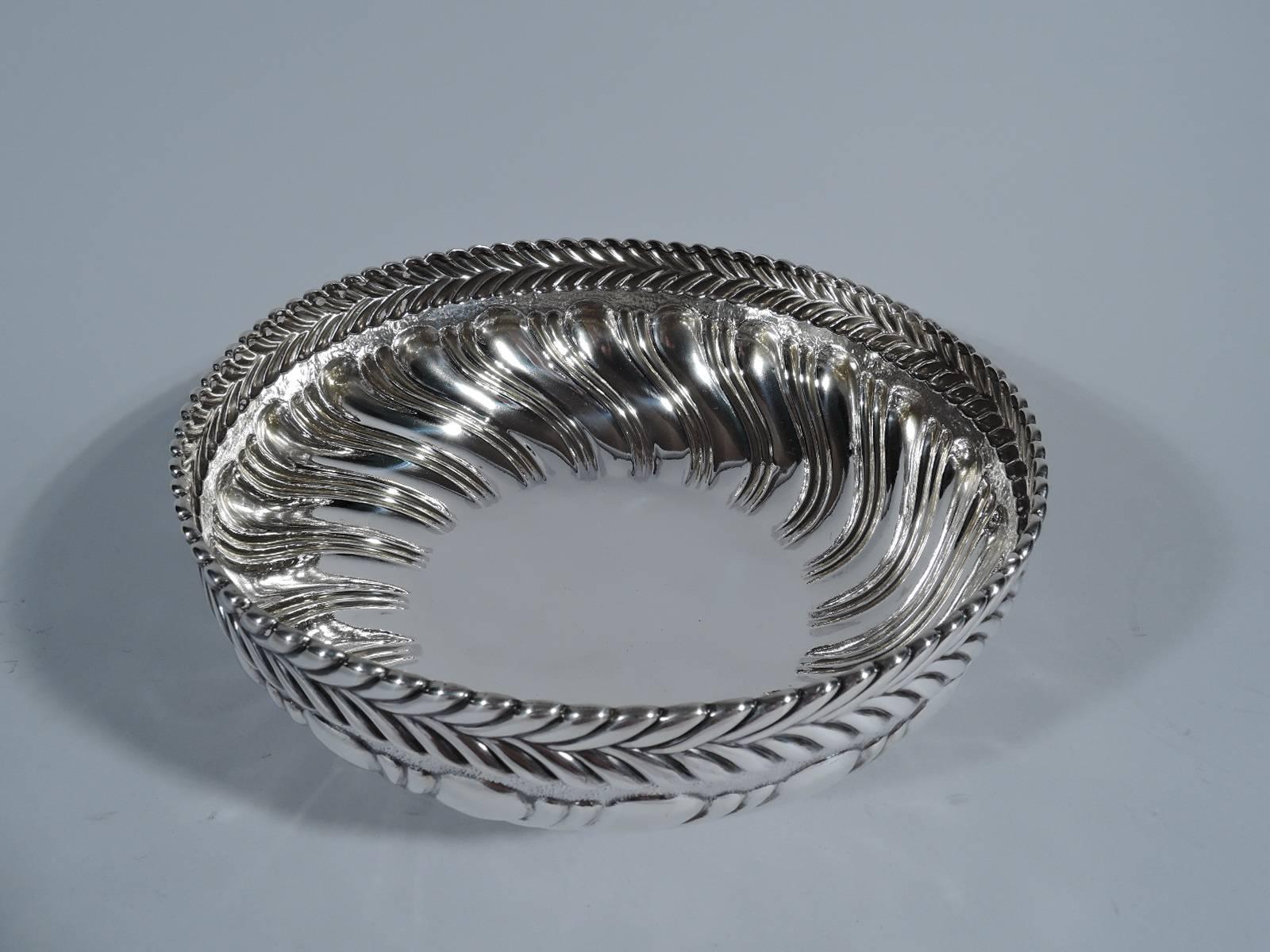 Sterling silver bowl with bold ornament. Made by Tiffany & Co. in New York, circa 1884. Round with curved sides and foot ring. Double narrow gadroons alternating with single wide gadroon. At rim chased and repousse band of stylized and imbricated