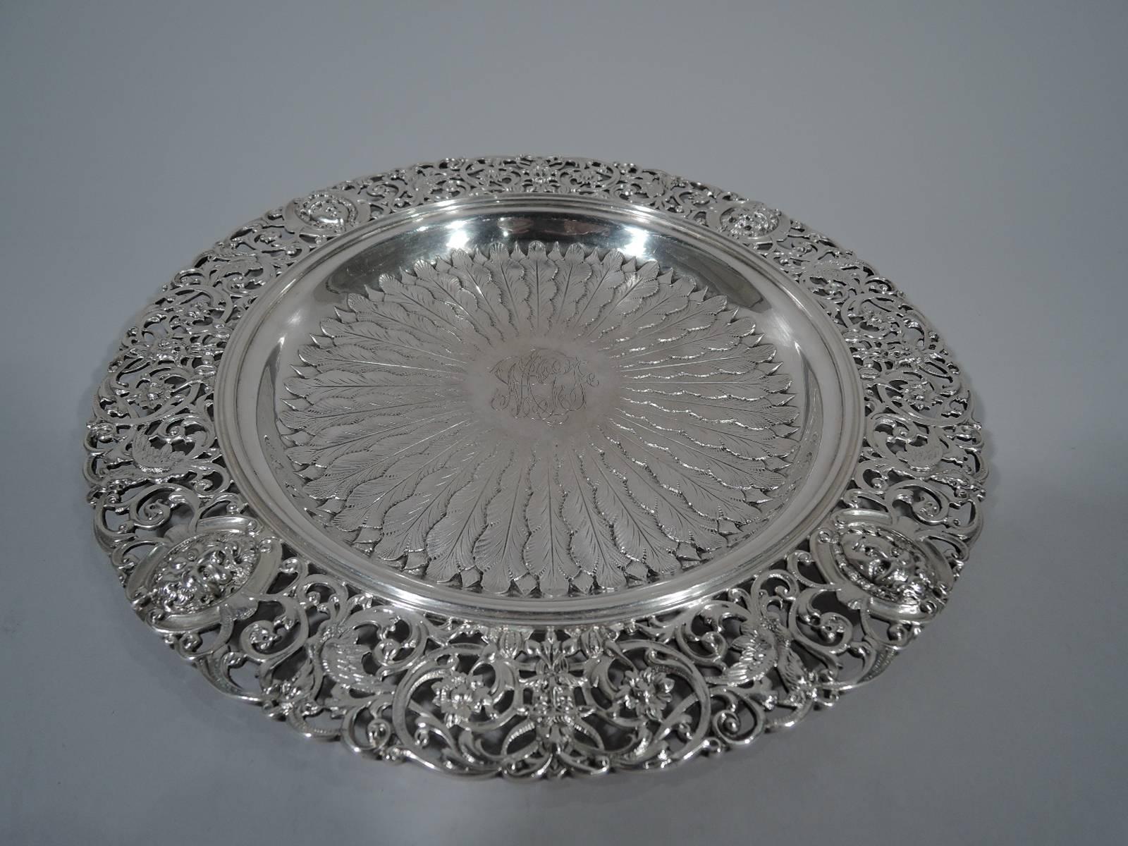 Pair of Renaissance Revival sterling silver trays. Made by Howard & Co. in New York in 1894. Each: Shallow well with chased radiating leaves and central frame with engraved interlaced script monogram. Wide pierced rim with Classical masks, gryphons,