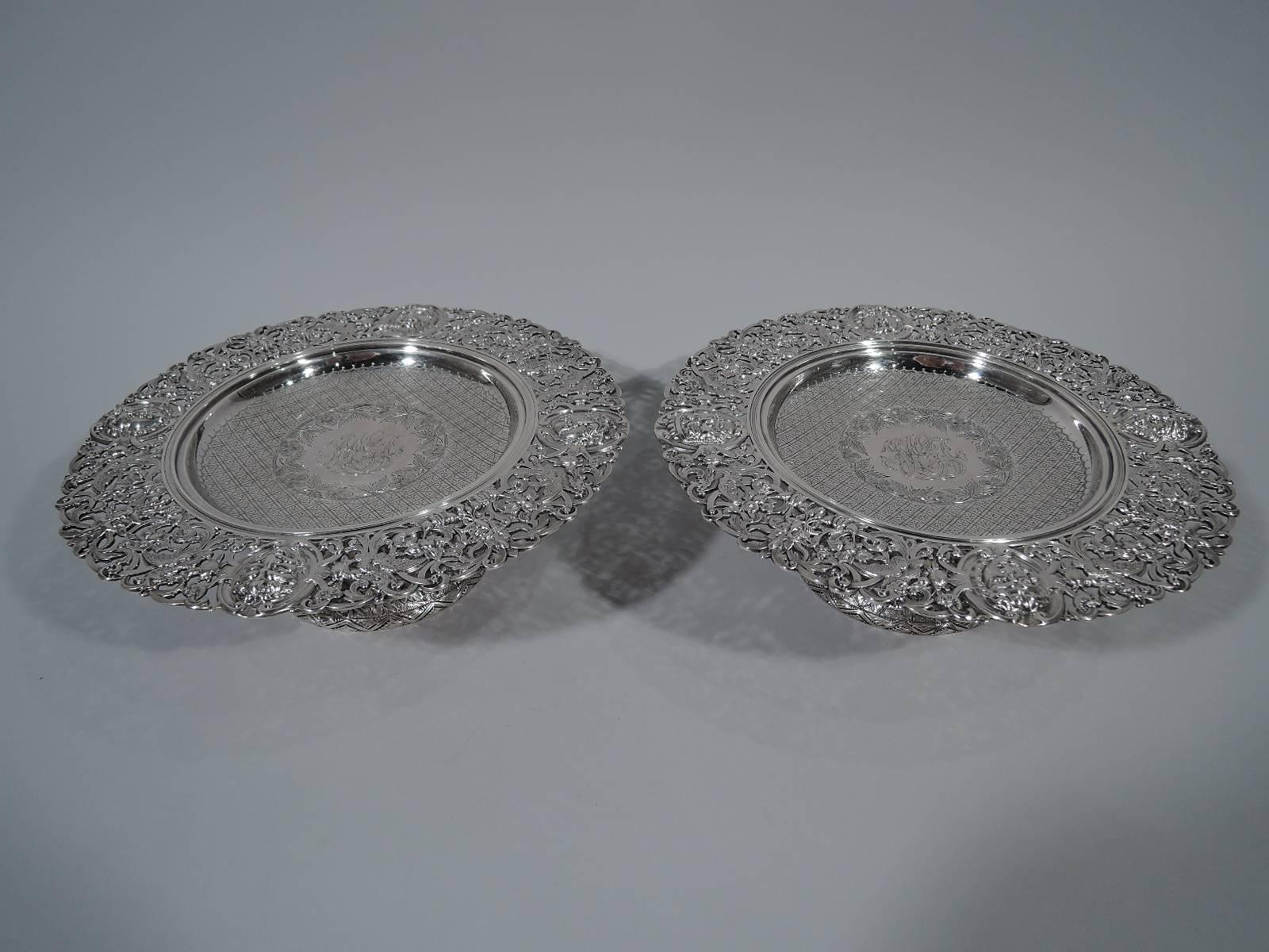 Pair of Renaissance Revival sterling silver compotes. Made by Howard & Co. in New York in 1889. Each: Shallow well with engraved diaper pattern and central floral wreath with interlaced script monogram. Wide pierced rim with Classical masks,