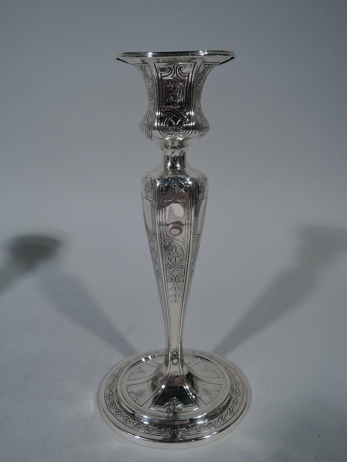 Pair of Edwardian sterling silver candlesticks. Made by Tiffany & Co. in New York, circa 1910. Each: Oval, faceted, and tapering shaft, stepped oval foot, and faceted and urn socket with plain oval rim. Acid-etched and stylized ornament. Hallmark