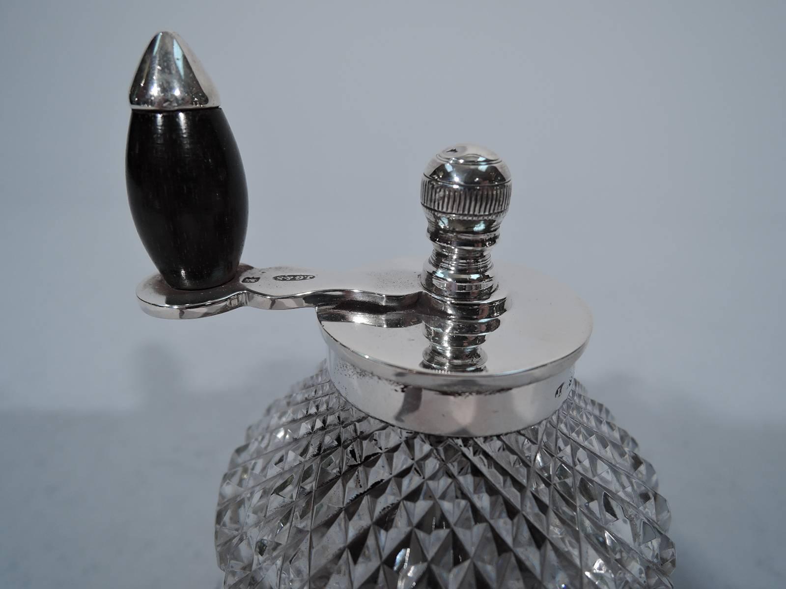 George V sterling silver and cut-glass pepper grinder. Made by Grinsell & Sons in Birmingham in 1926. Clear glass bowl with cut diaper pattern mounted to raised and spread base. Flat circular cover and rotating handle with stained wood finial.