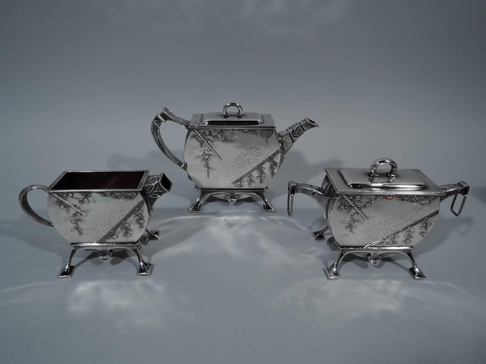 Early Japonesque sterling silver tea set. Made by Tiffany & Co. in New York. This set comprises teapot, creamer, and sugar. 

Each: Flat sides with curved ends and bottom set in four-legged frame with block feet. Teapot and sugar have flat cover