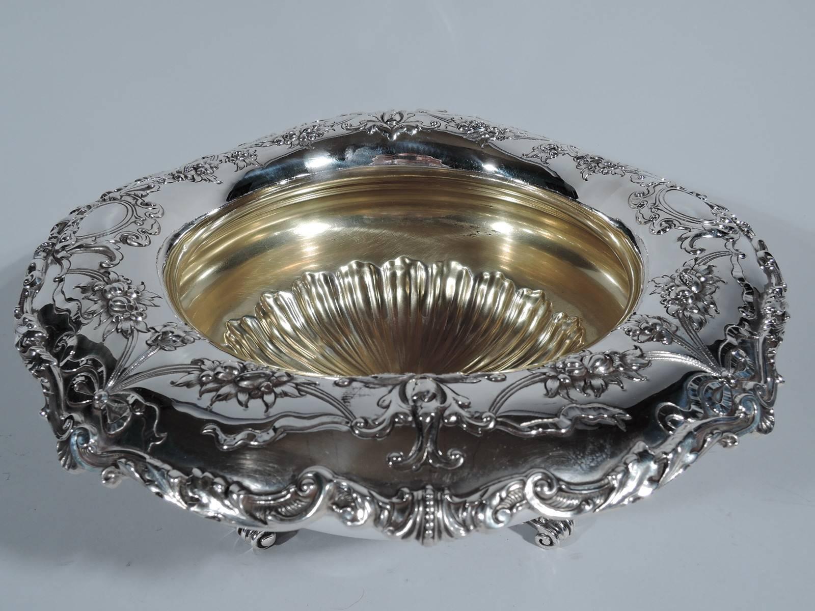 Edwardian sterling silver centerpiece bowl. Made by Gorham in Providence, circa 1910. Bellied with turned-down rim decorated with garlands and ribbon as well as applied scrolls and shells. Interior gilt with radiating flutes. Four volute scroll