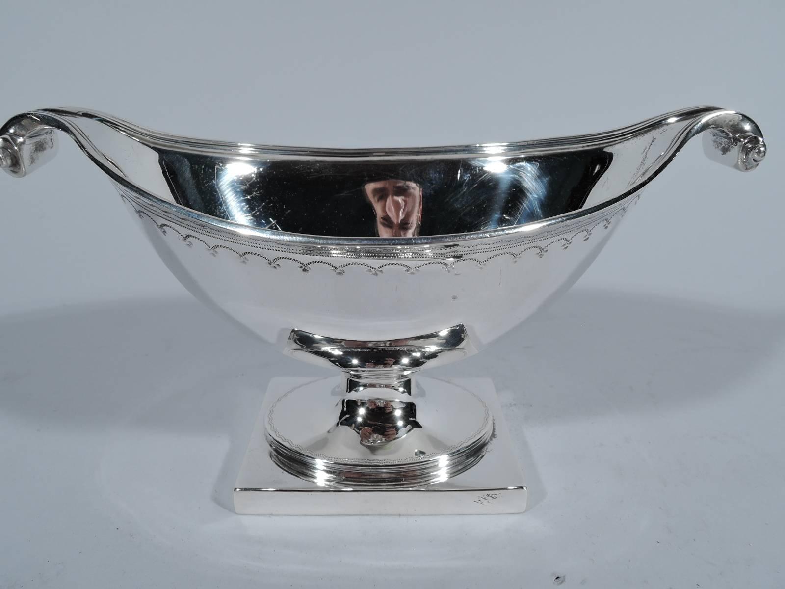 Pair of neoclassical sterling silver sweet meat bowls. Made by Howard & Co. in New York, circa 1910. Each: Boat-form bowl with volute scrolls on oval foot mounted to rectangular base. Engraved bands of lines, arches, and waves. Reeded bowl and foot