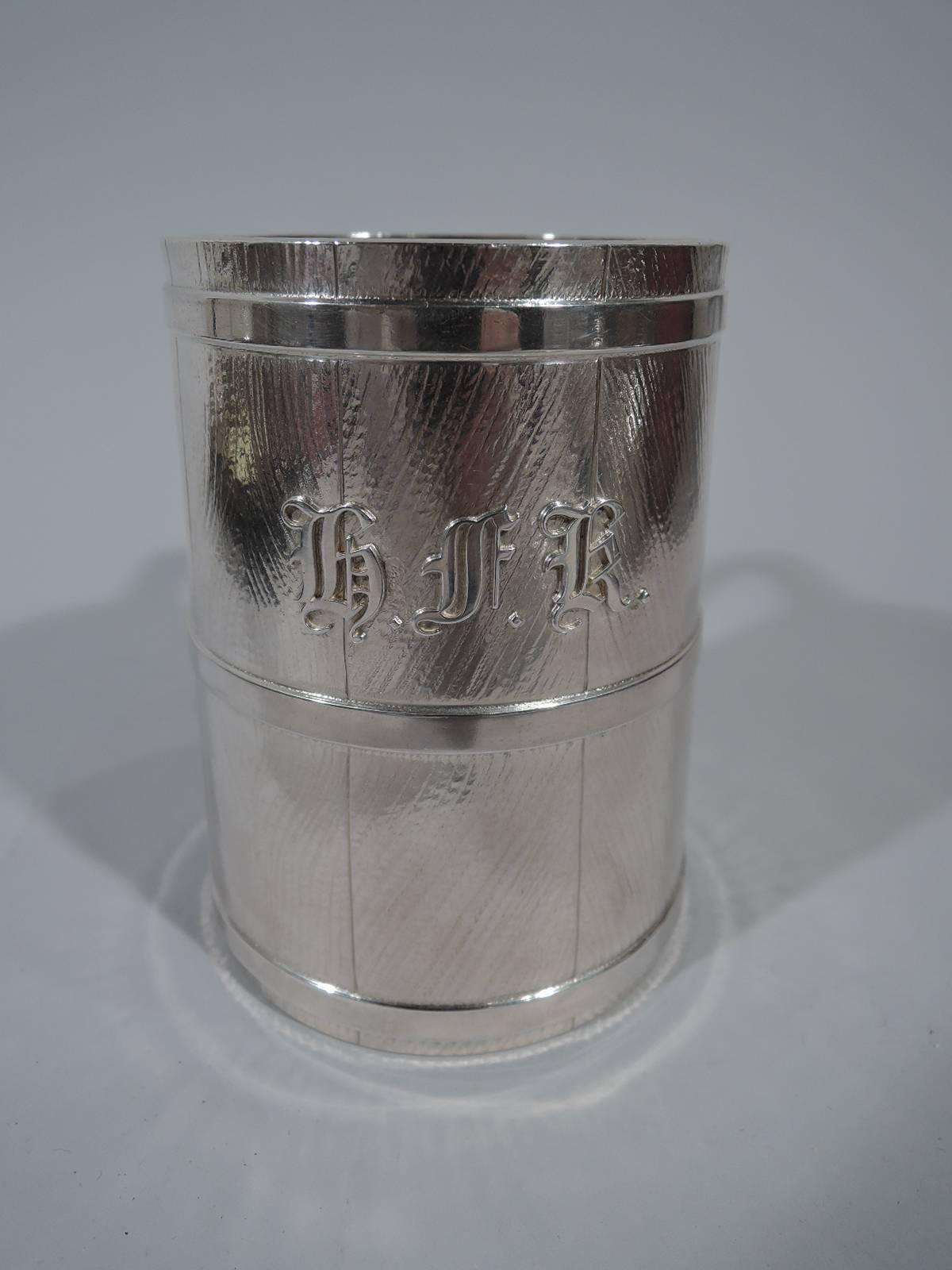 Early sterling silver youth tankard. Made by Tiffany & Co. in New York. Upward tapering sides in form of grainy staves with hoops. Scroll bracket handle. Gilt interior suggestive of a golden brew. Applied script initials HFK with related