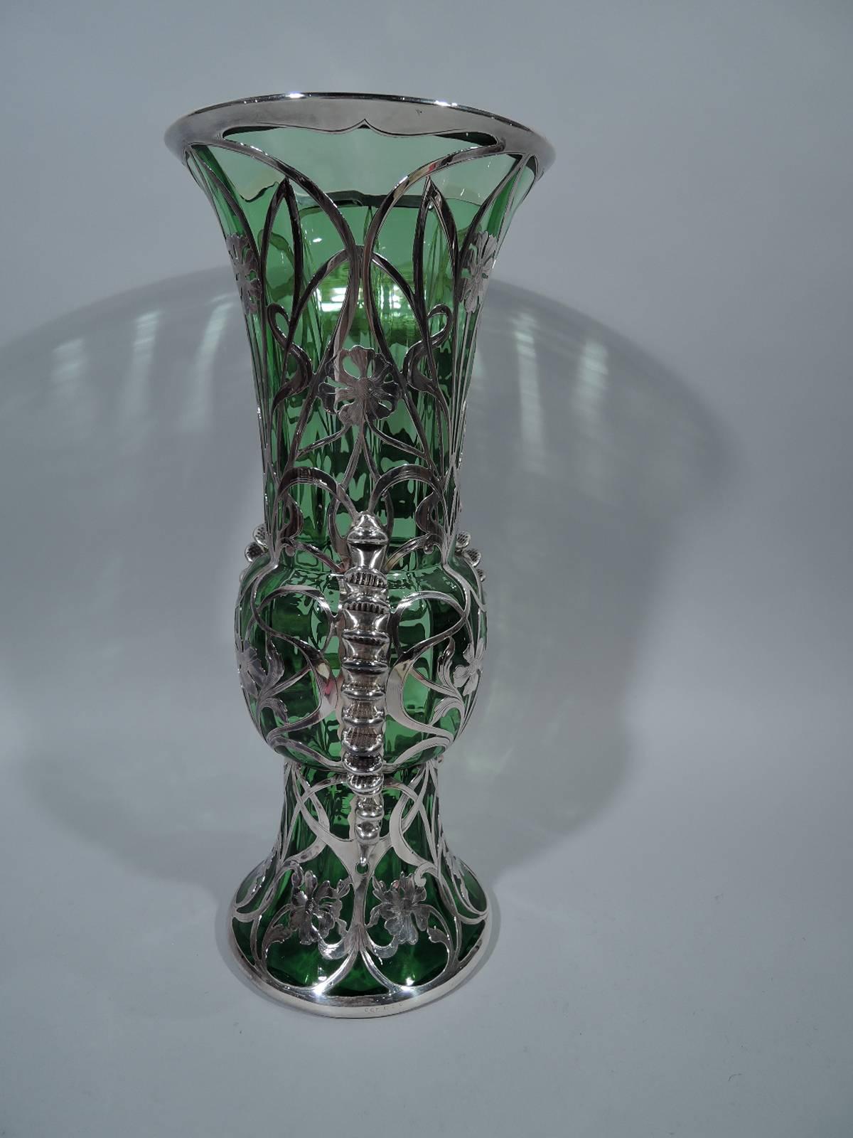 Tall and unusual glass vase with silver overlay. Made by Gorham in Providence, circa 1900. Baluster with wide mouth and raised and spread foot. Entwined and whiplash tendrils with flowers. Surface ornament contrasts with notched brackets applied to