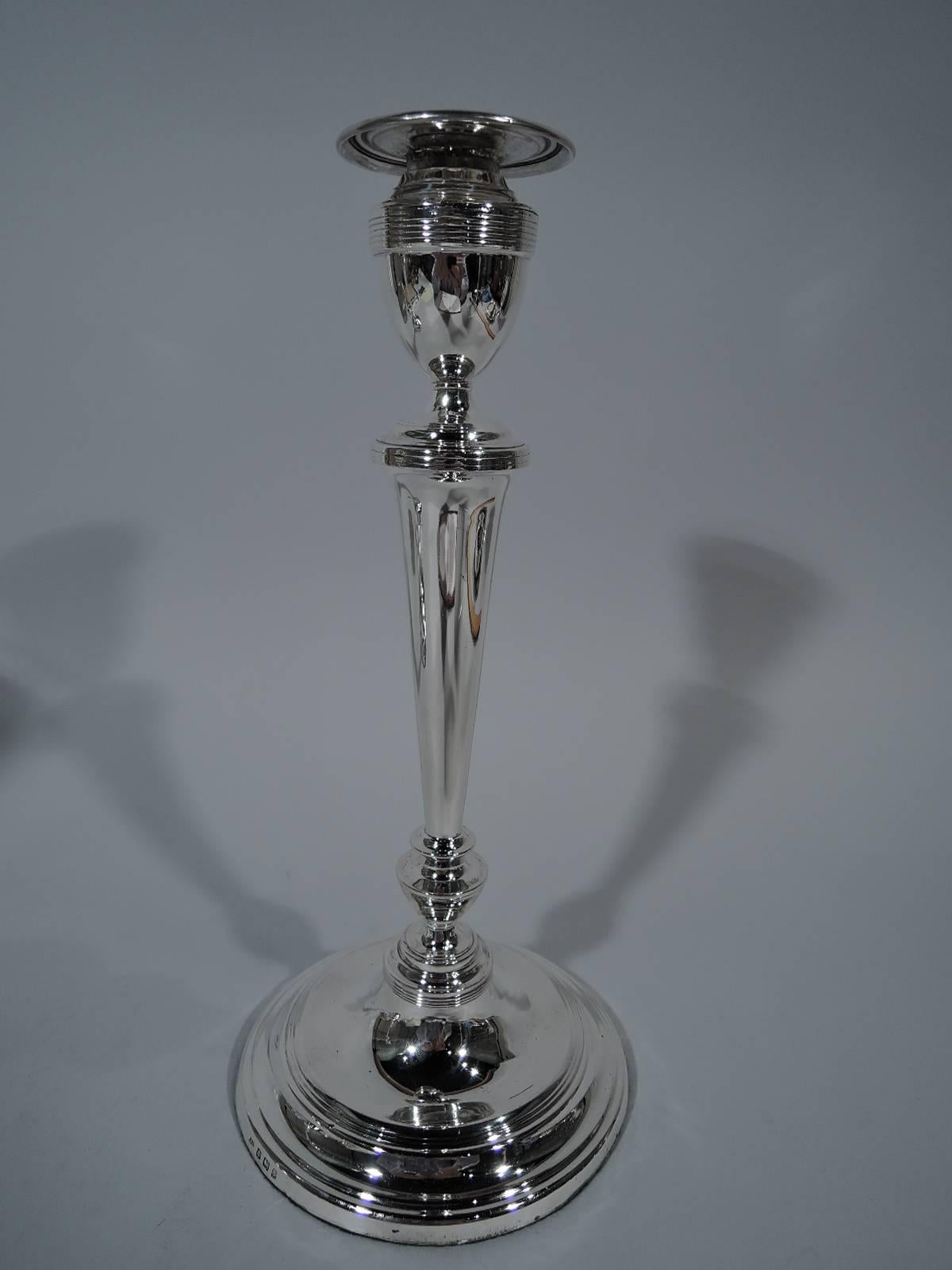 Pair of Edwardian sterling silver candlesticks. Made by Israel Sigmund Greenberg in Birmingham in 1905. Each: Straight and tapering shaft on knops on raised foot. Reeded urn socket with detachable bobeche. Hallmarked. Weighted.