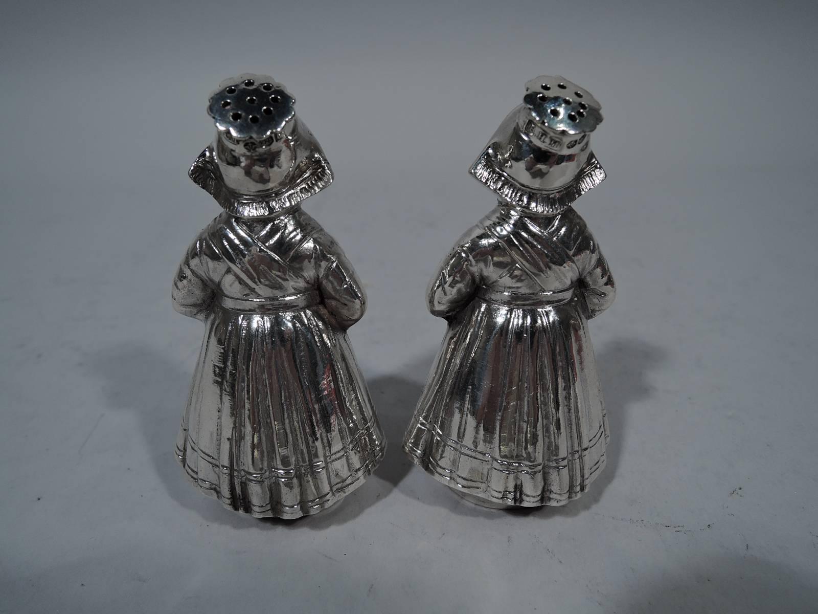 Pair of German sterling silver figural salt and pepper shakers, circa 1920. Each: A sturdy country girl in peaked cap and wood shoes peeking out from under voluminous skirts. Cap top pierced and detachable. Hallmark includes mark for London importer