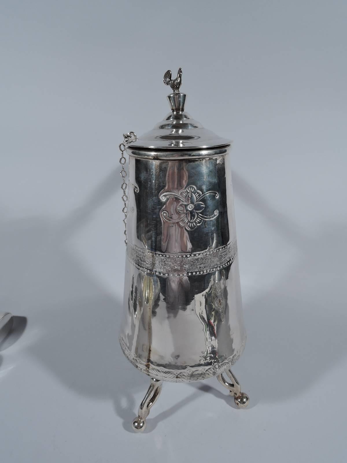 Traditional South American silver hot drink pot. Upward tapering sides with tooled naïve ornament with flowers, leaves, and stippled band with pointille borders. Stained-wood side handle with silver mount and 3 open supports with ball terminals.
