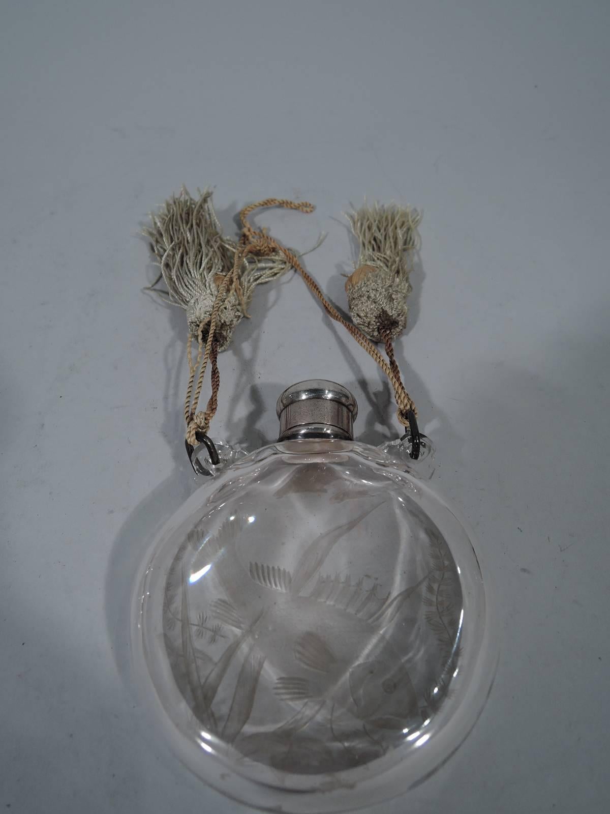 Japonesque sterling silver and glass perfume. Made by Tiffany & Co. in New York, circa 1878. Circular with flat sides and short neck. On front intaglio-cut fish (coy) and sea grasses. Threaded bun cover engraved with interlaced script monogram.