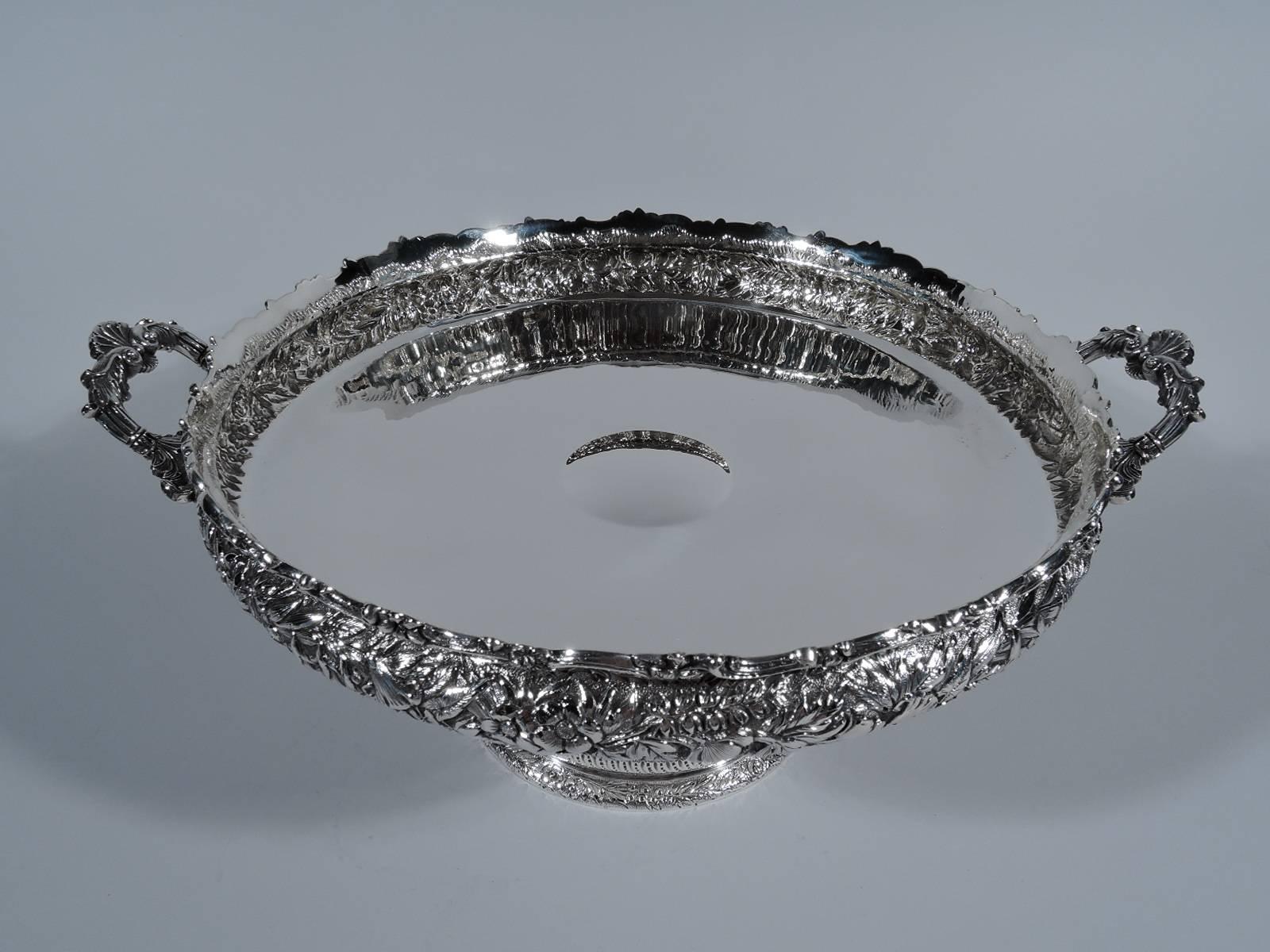 Sterling silver footed centrepiece bowl. Made by Tiffany & Co. in New York, circa 1875. Shallow bowl with bellied sides, bracket side handles, short stem and domed foot. Plain well. Sides and foot have beautiful floral repousse on stippled ground.