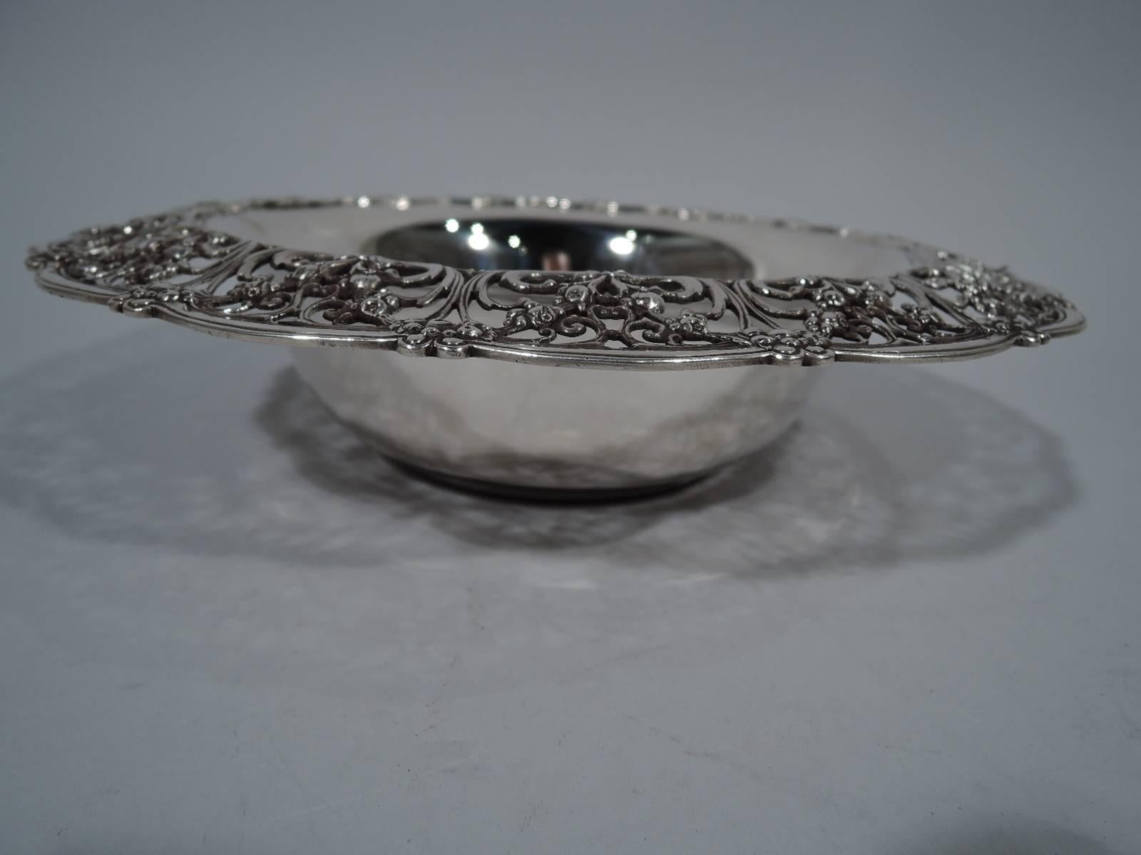 Edwardian sterling silver bowl. Made by Tiffany & Co. in New York, circa 1910. Round and solid well. Scalloped turned-down rim with pierced scrolls and flowers. Fresh and pretty. Hallmark includes pattern no. 17790A (first produced in 1910) and