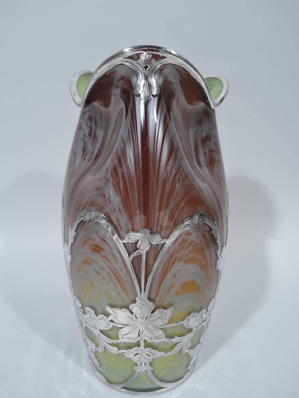 Beautiful art glass vase with silver overlay by historic Czech maker Loetz, circa 1900. Ovoid with pinched and asymmetrical mouth with shaded color and white feathering. Vase interior green. Silver overlay in form of floral arcade. Glass unsigned.